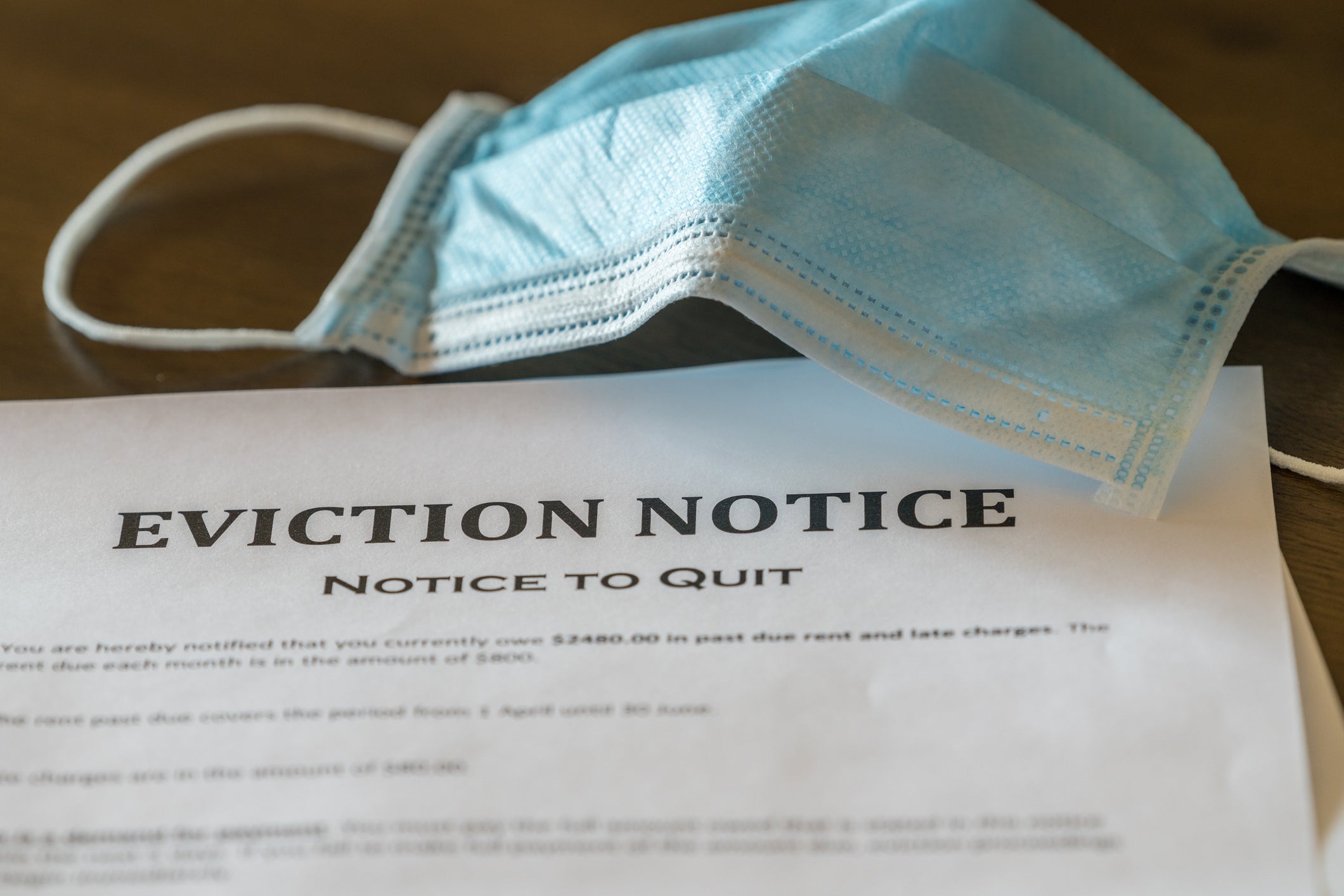 Eviction notice and a face mask on a wooden table.