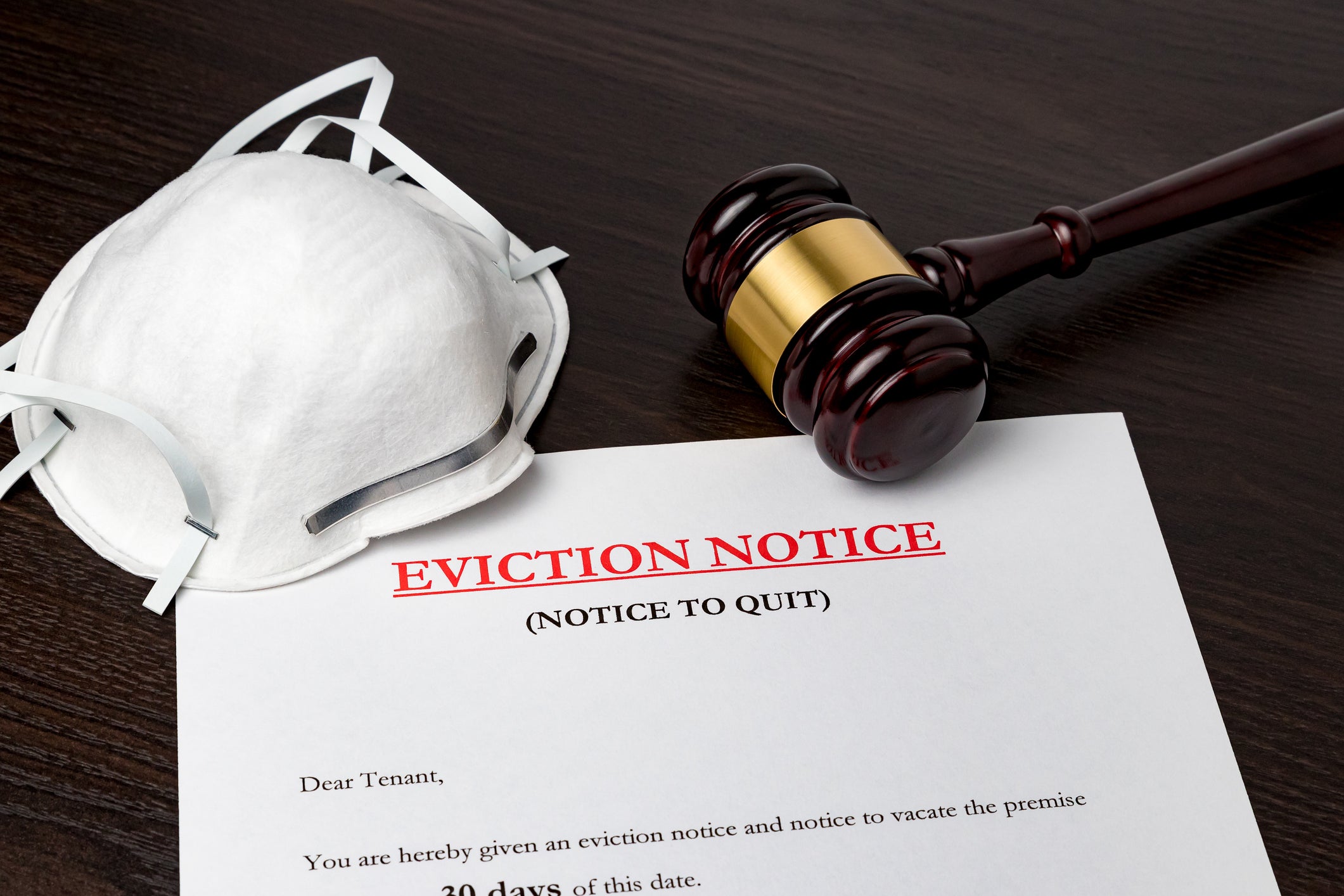 Eviction notice document with gavel and N95 face mask on a table.