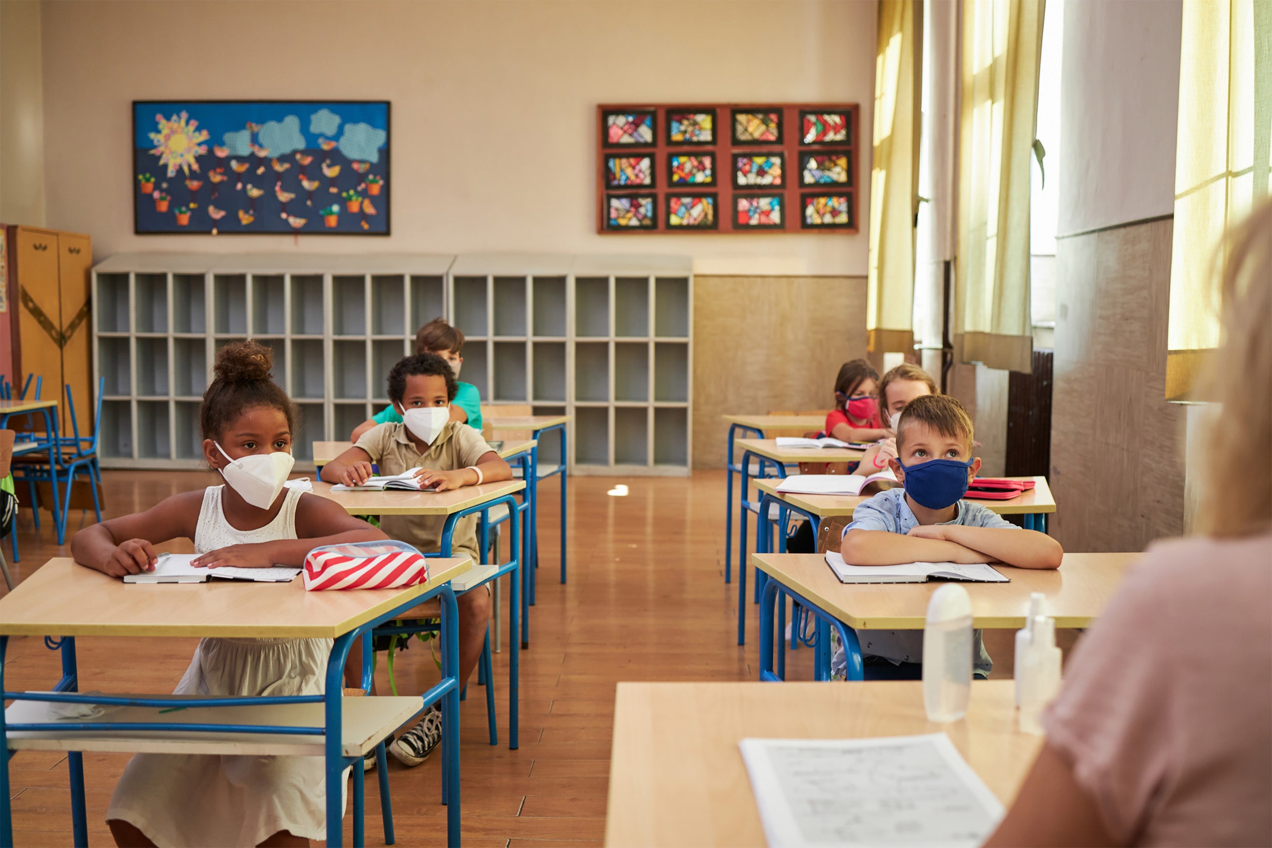 Group of elementary children studying with a teacher at school during coronavirus pandemic