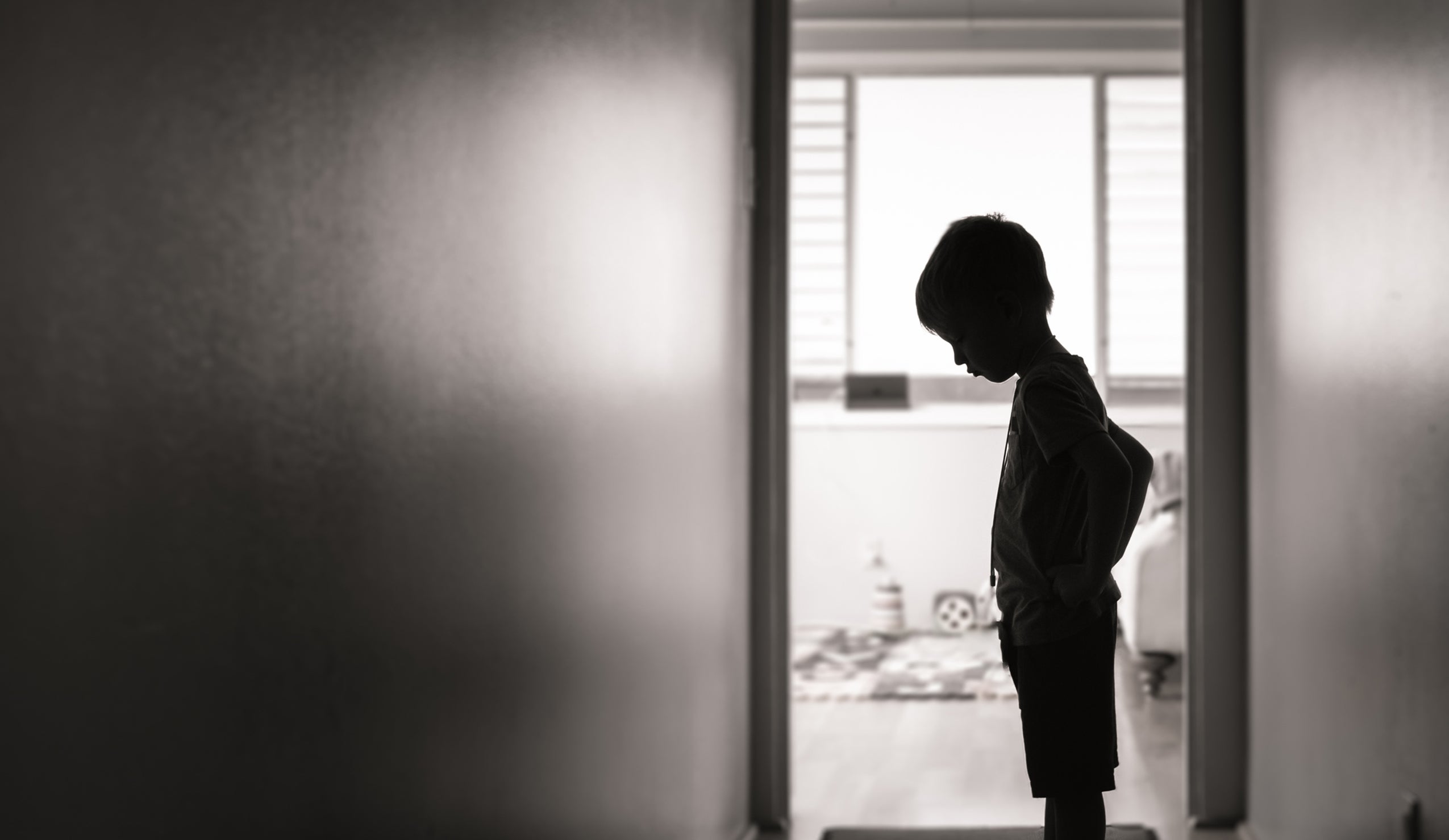 Boy standing in silhouette in a hallway