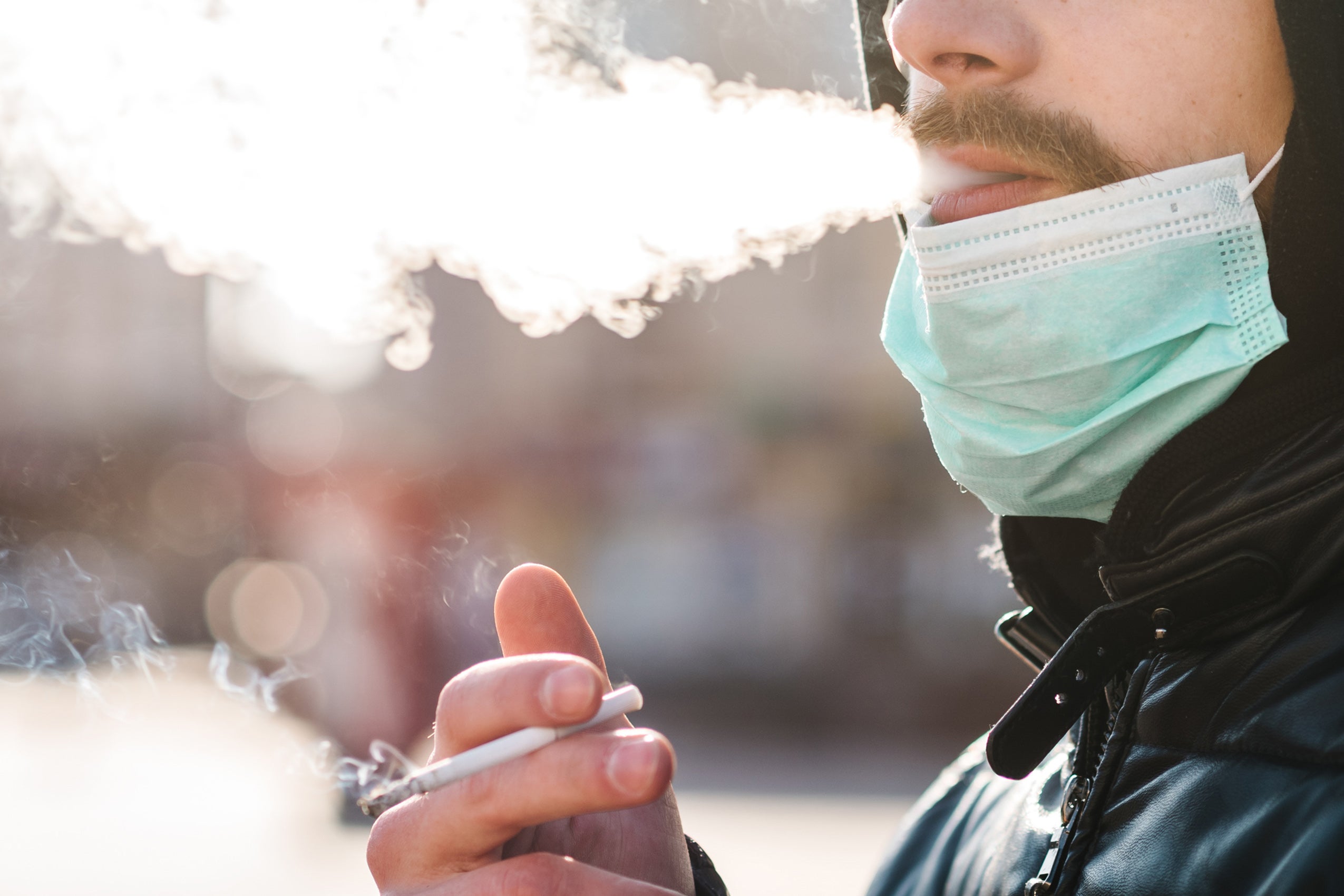 Closeup of man smoking and wearing a mask