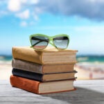 Sunglasses on top of a stack of books at the beach