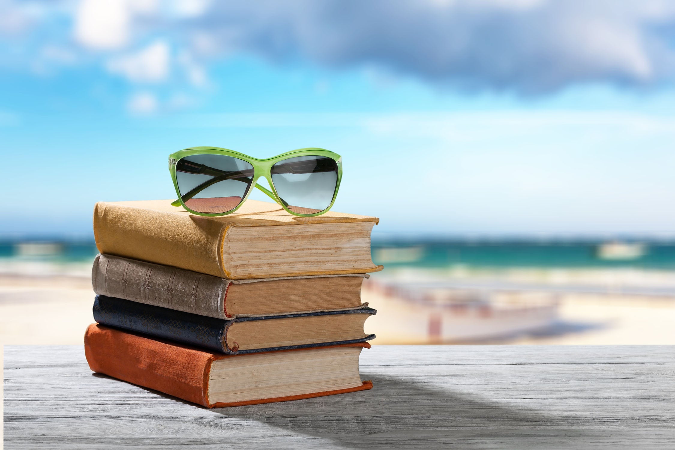 Sunglasses on top of a stack of books at the beach