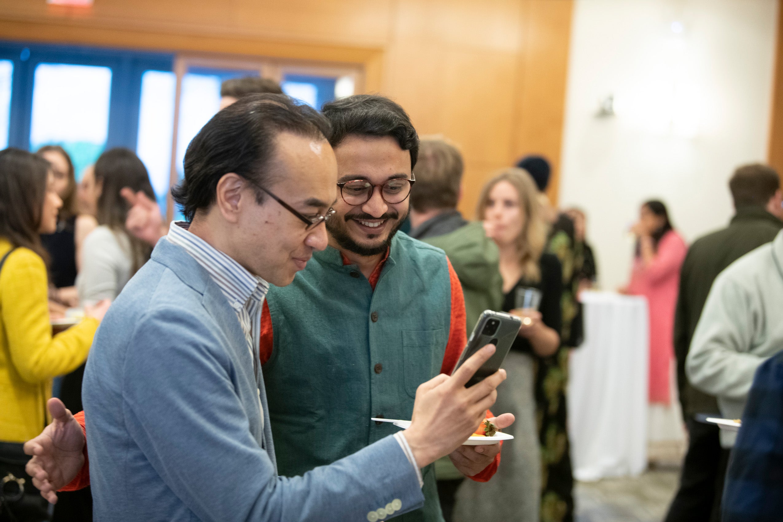 Two students at an event look at something on a cell phone