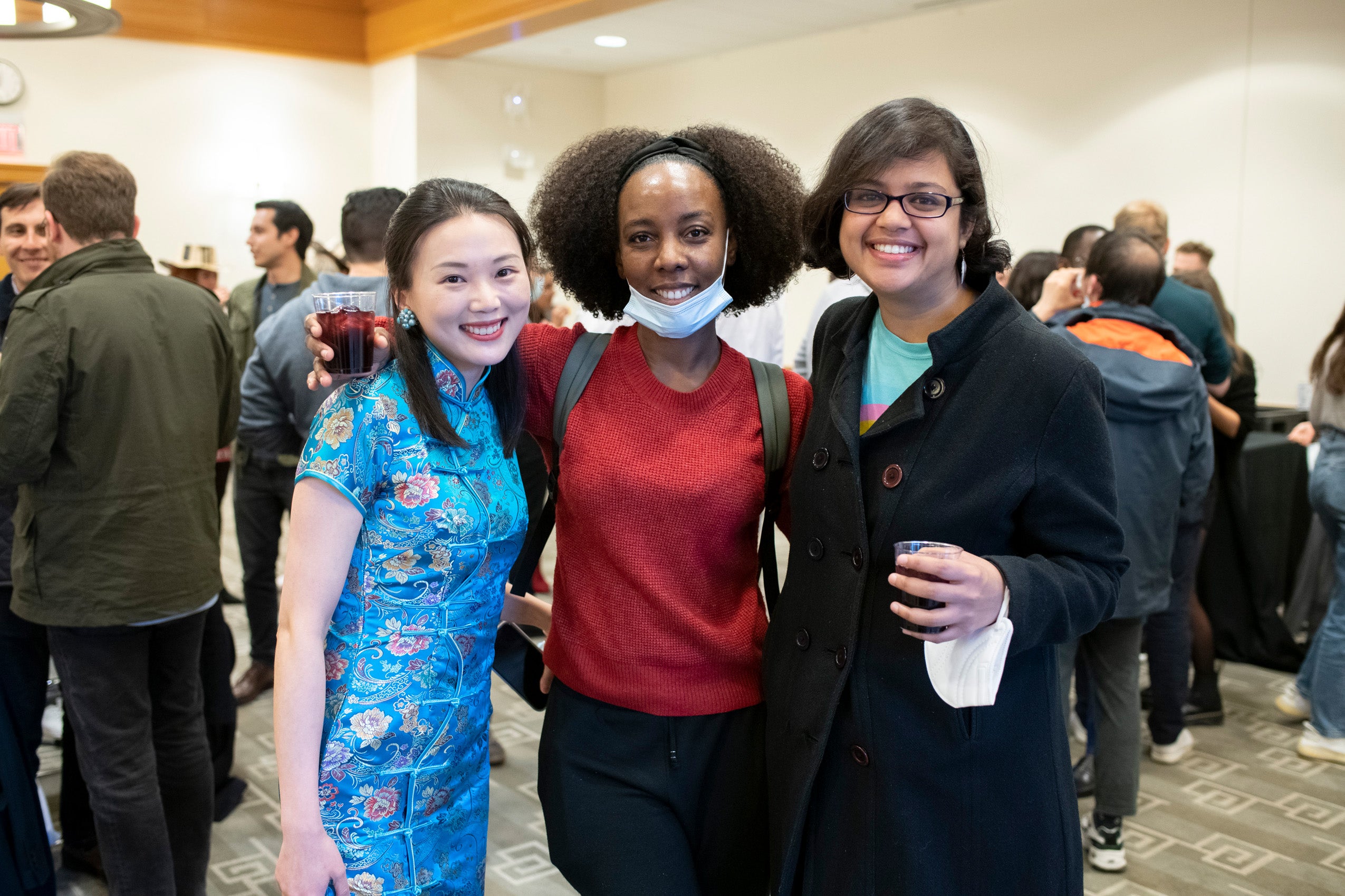 Three female graduate students pose for a photo at an event