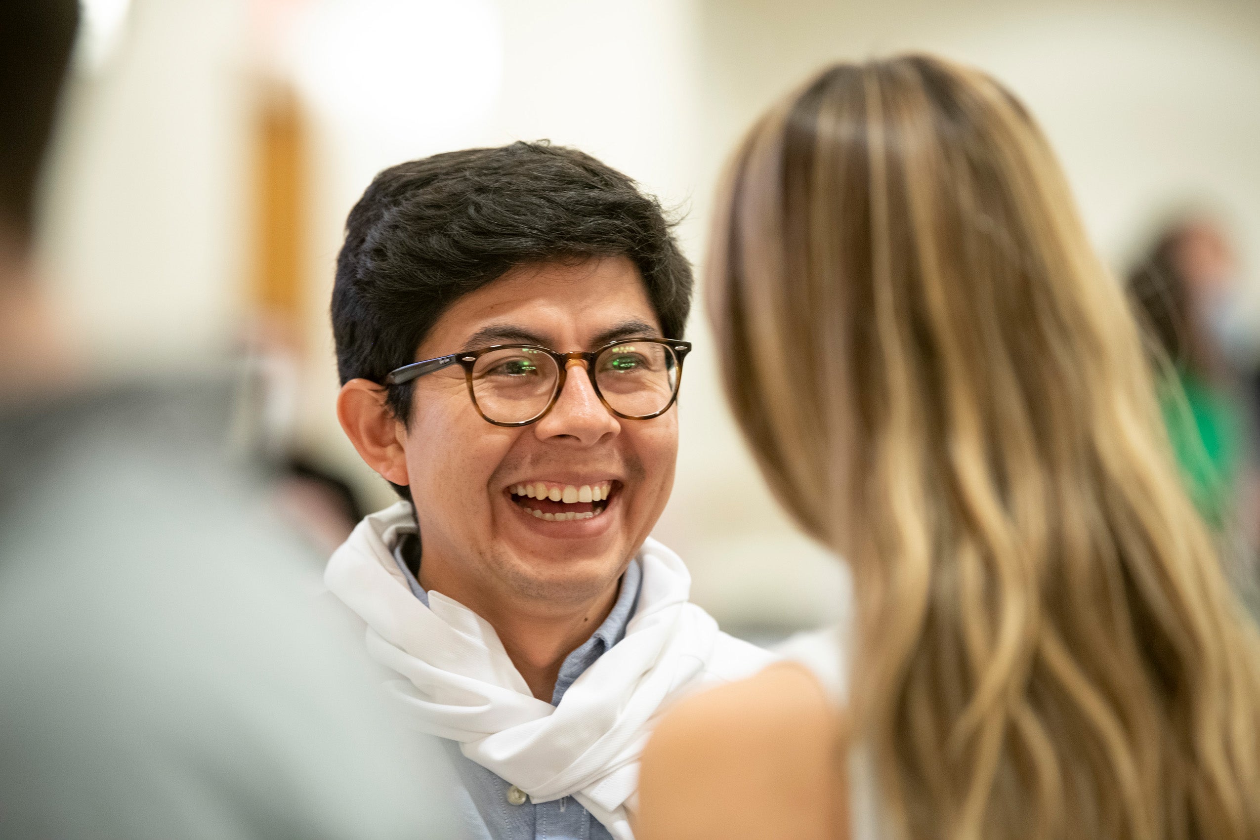 A student smiles as he talks to another student at an event.