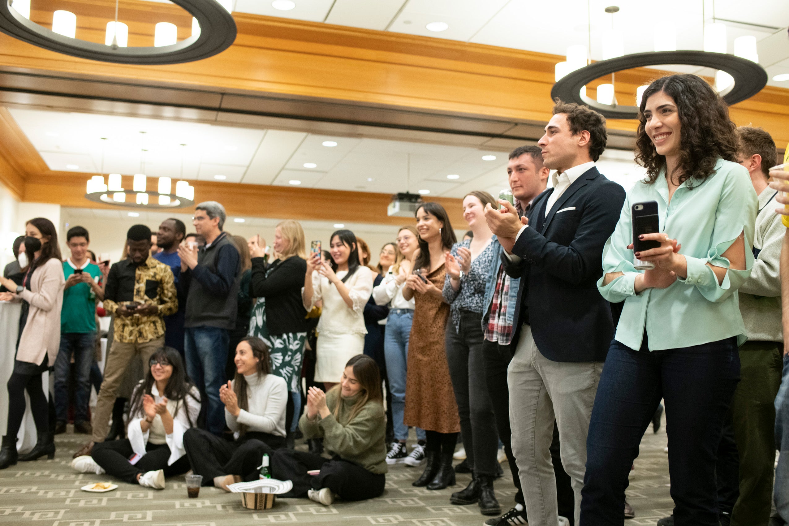 A group of students watch an event and clap