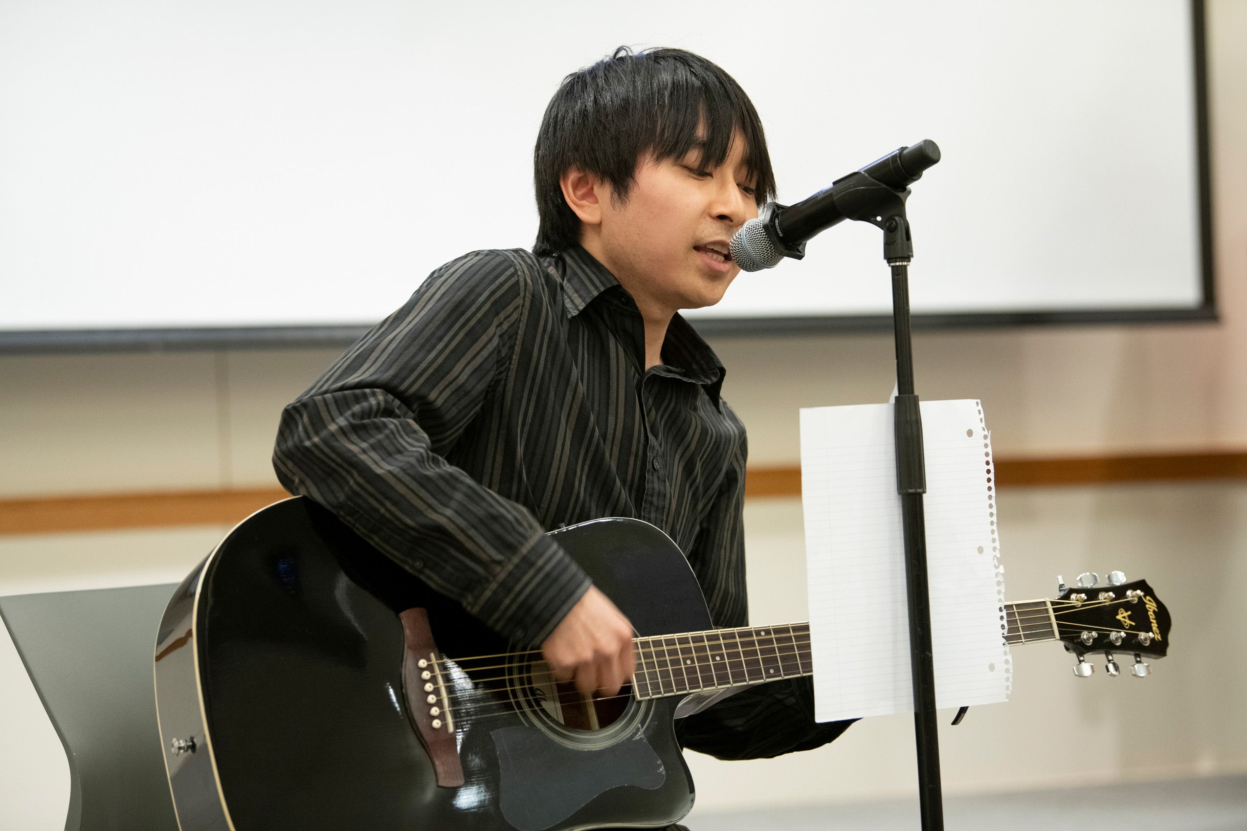 A student sings and plays guitar at an event