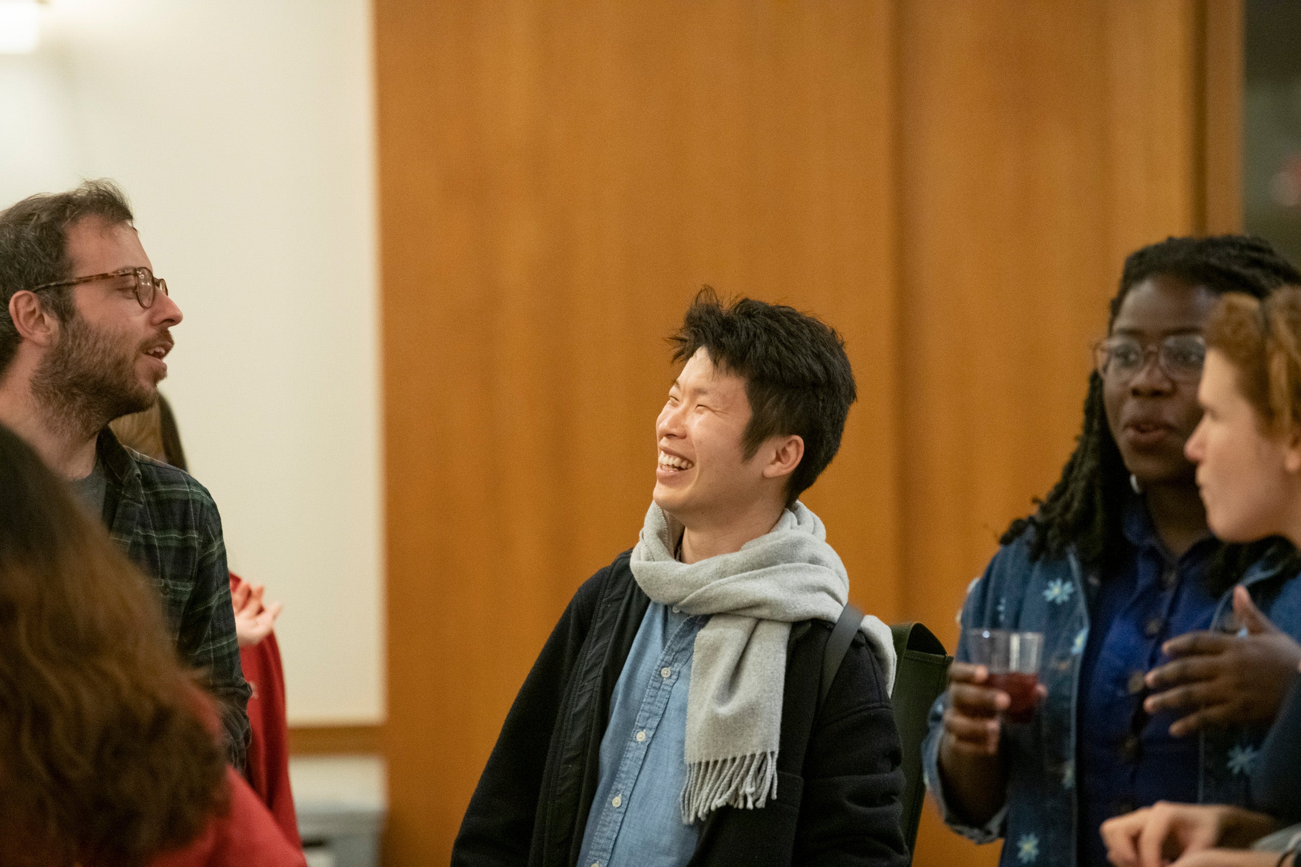 A student smiles as he speaks with another student at an event
