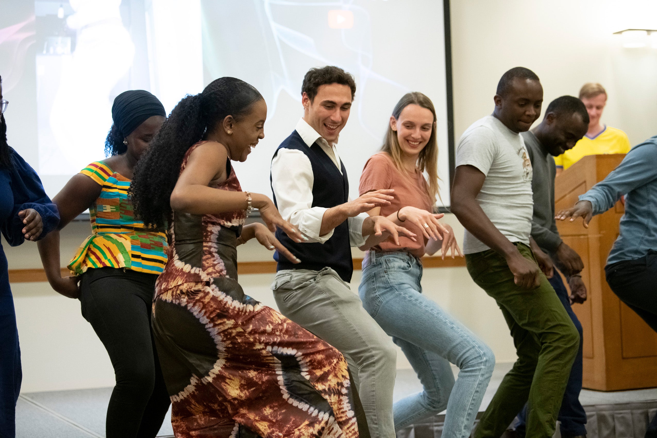 A group of students enjoy learning a dance moves taught by one of their classmates at an event