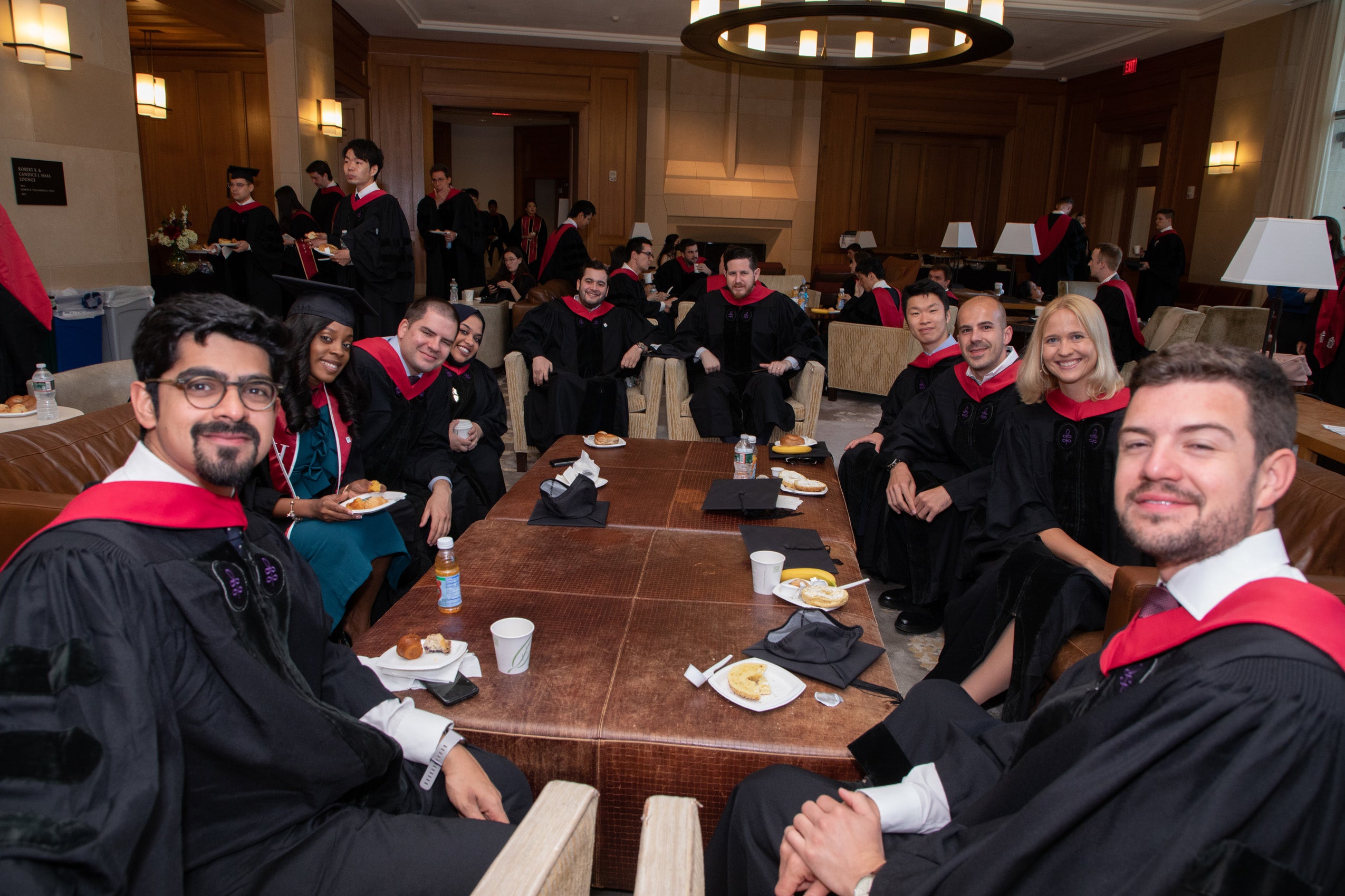 Group of students in commencement caps and gowns sit around a table in the WCC