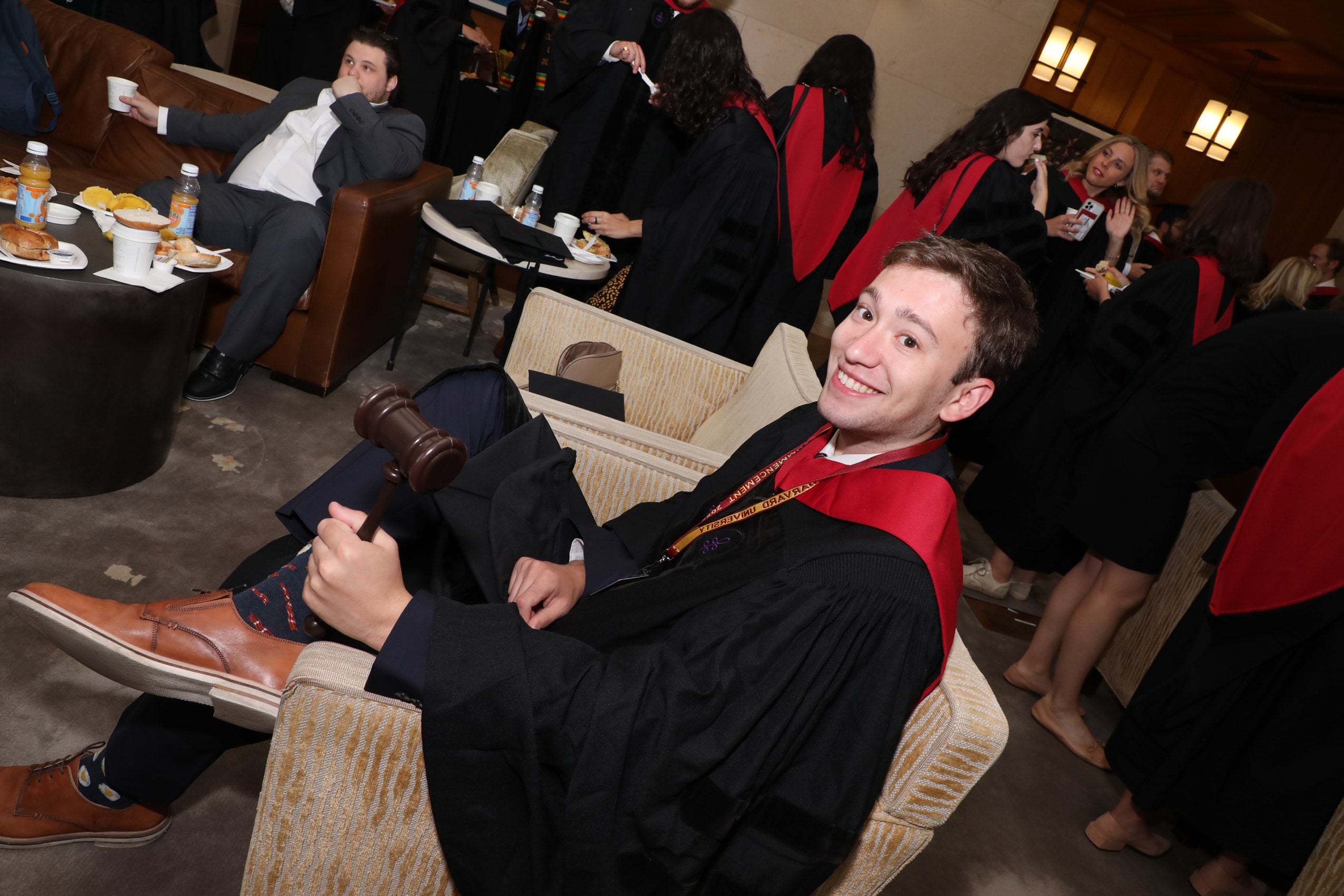 A man sitting on a couch wearing a cap and gown smiles for the camera