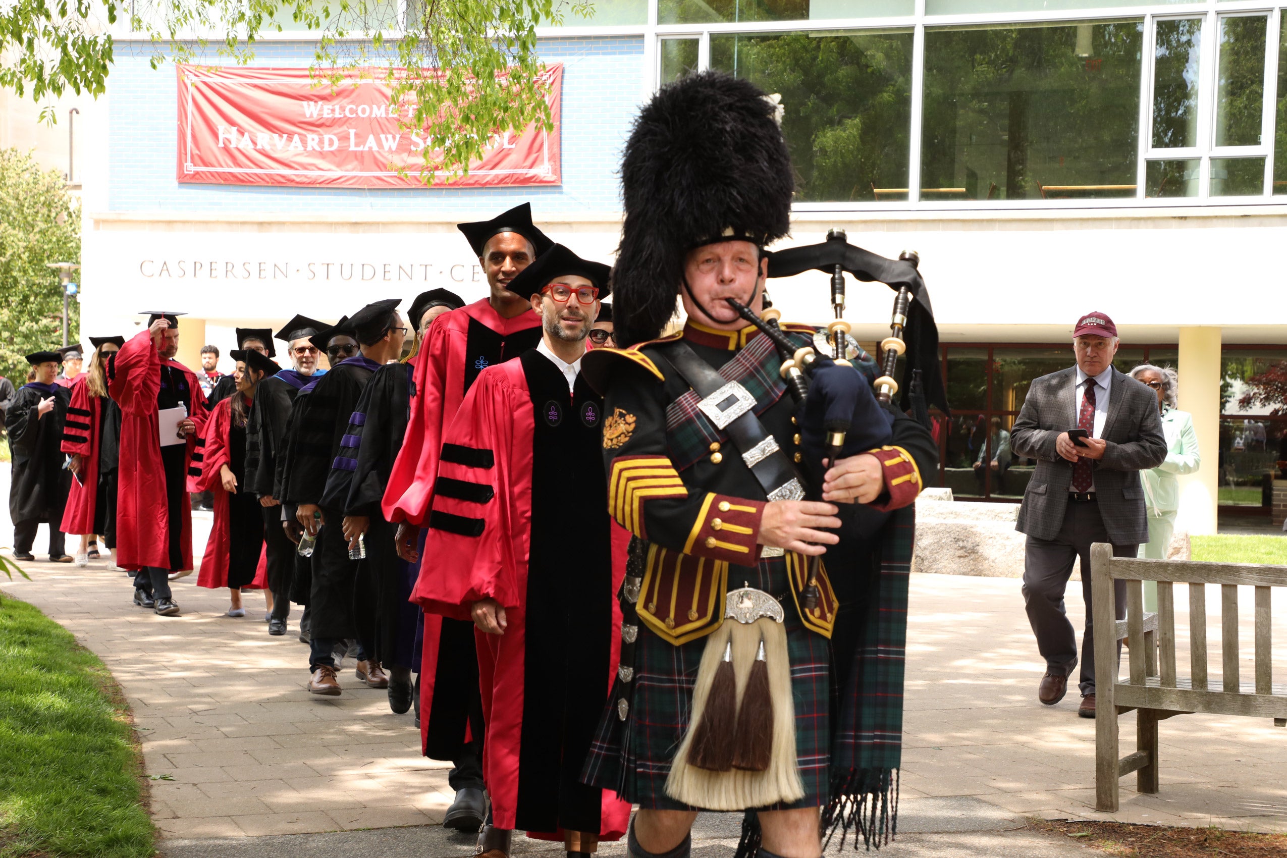 A processional of faculty led through Holmes Field by a bagpiper