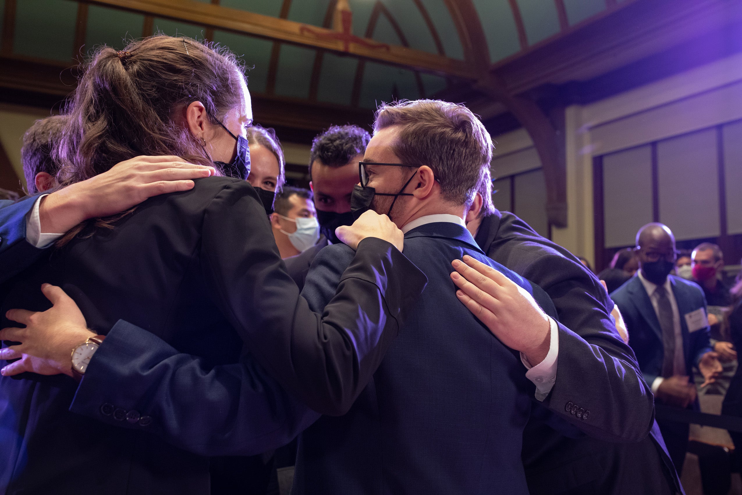 Group of men and women celebrate in a supportive group huddle