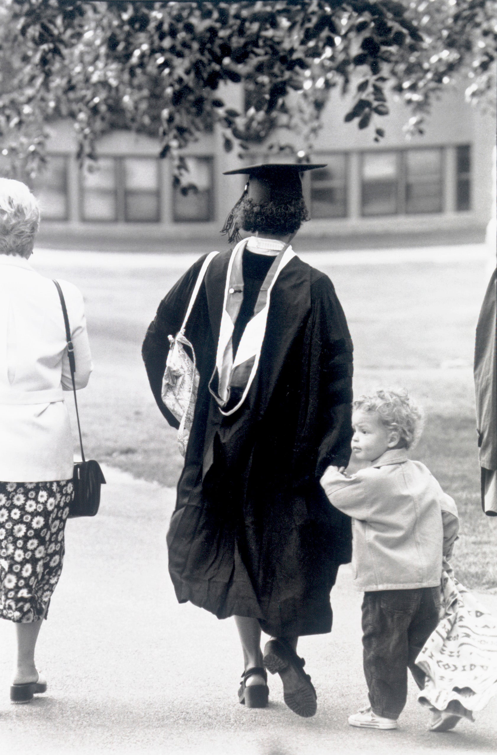 Woman walks holding hand of child, 1990