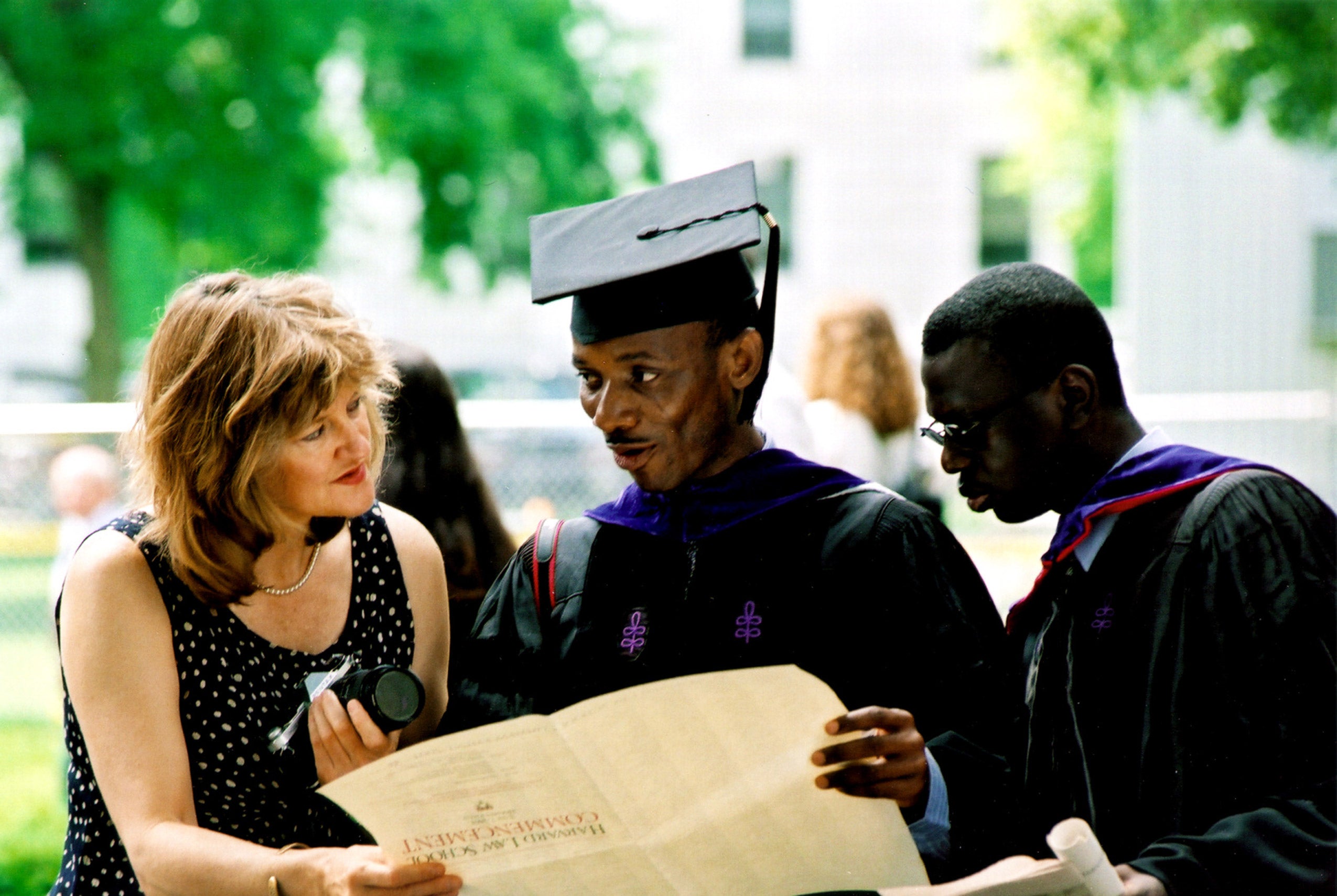 Graduate in black robes shows a Commencement program to a woman