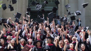 A large group of students throw up their Commencement caps at graduation