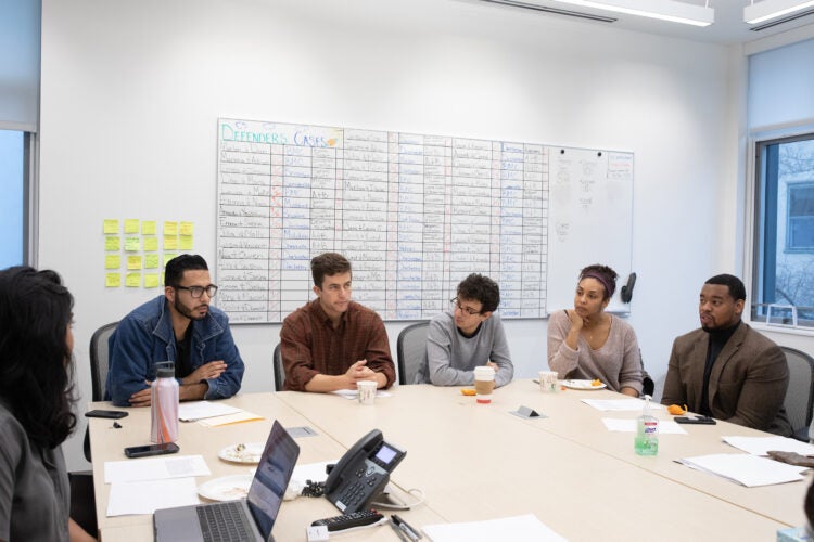Six people gathered around a table in a conference room.