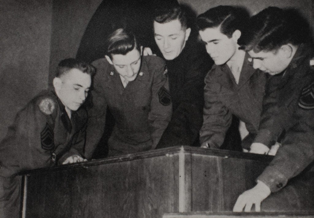 a group of men leaning over a desk