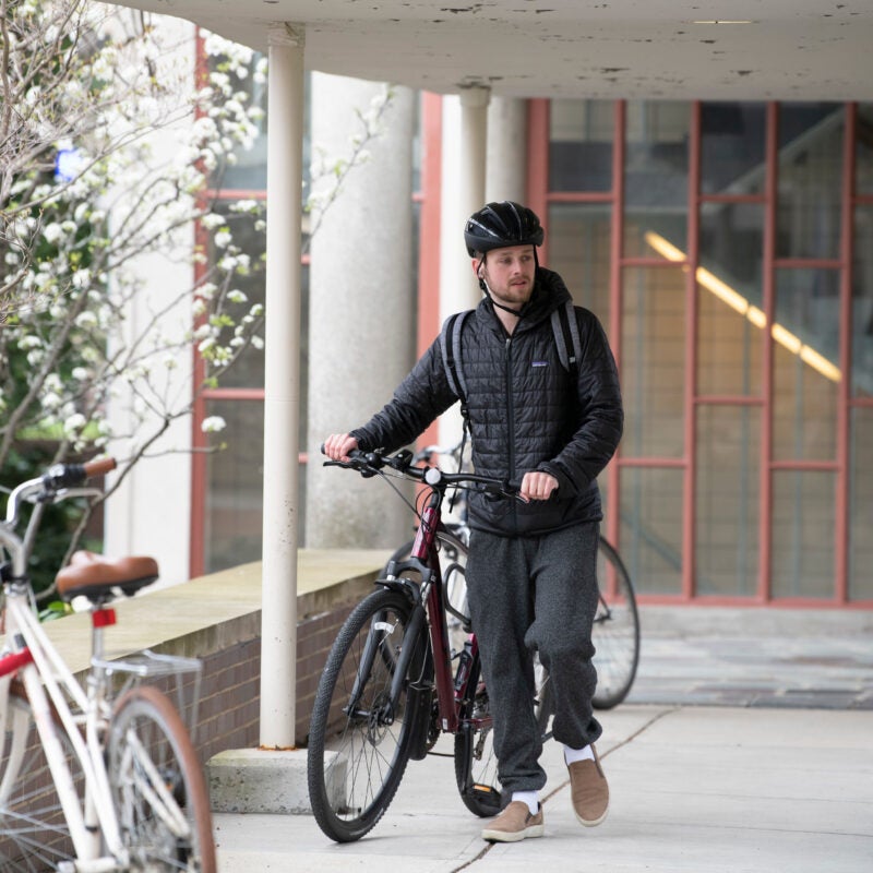 A Student walking his bicycle on campus