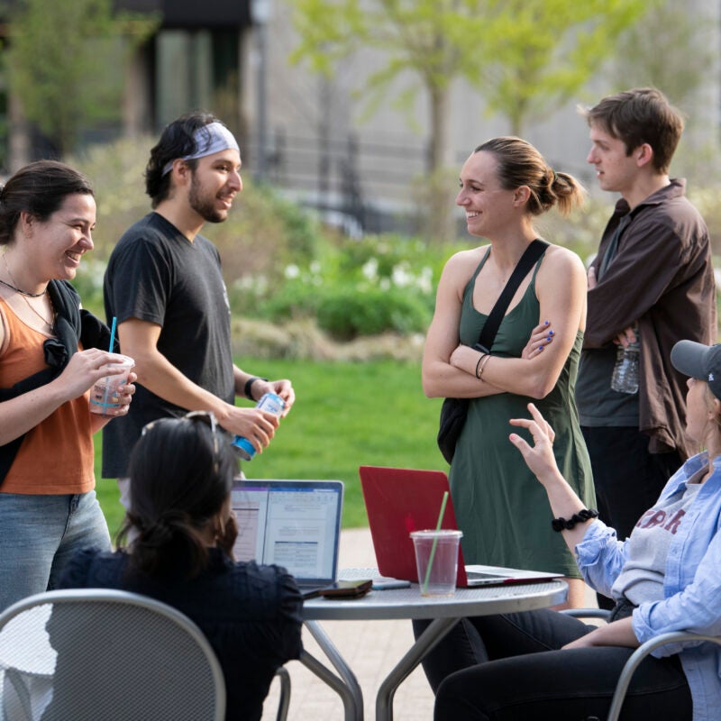 A group of students chatting around an outdoor table