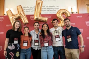 A group of LL.M. students pose in front of a back drop and gold HLS balloons