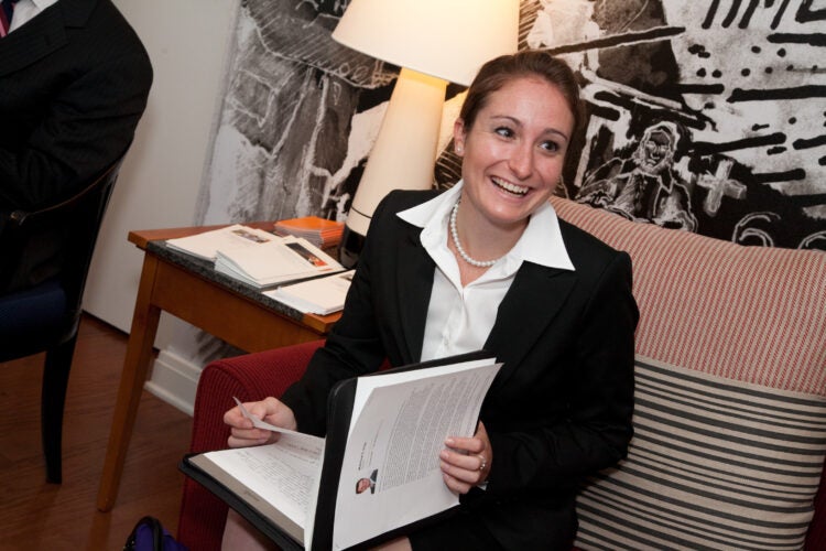 person in a suit smiling and reviewing paper materials