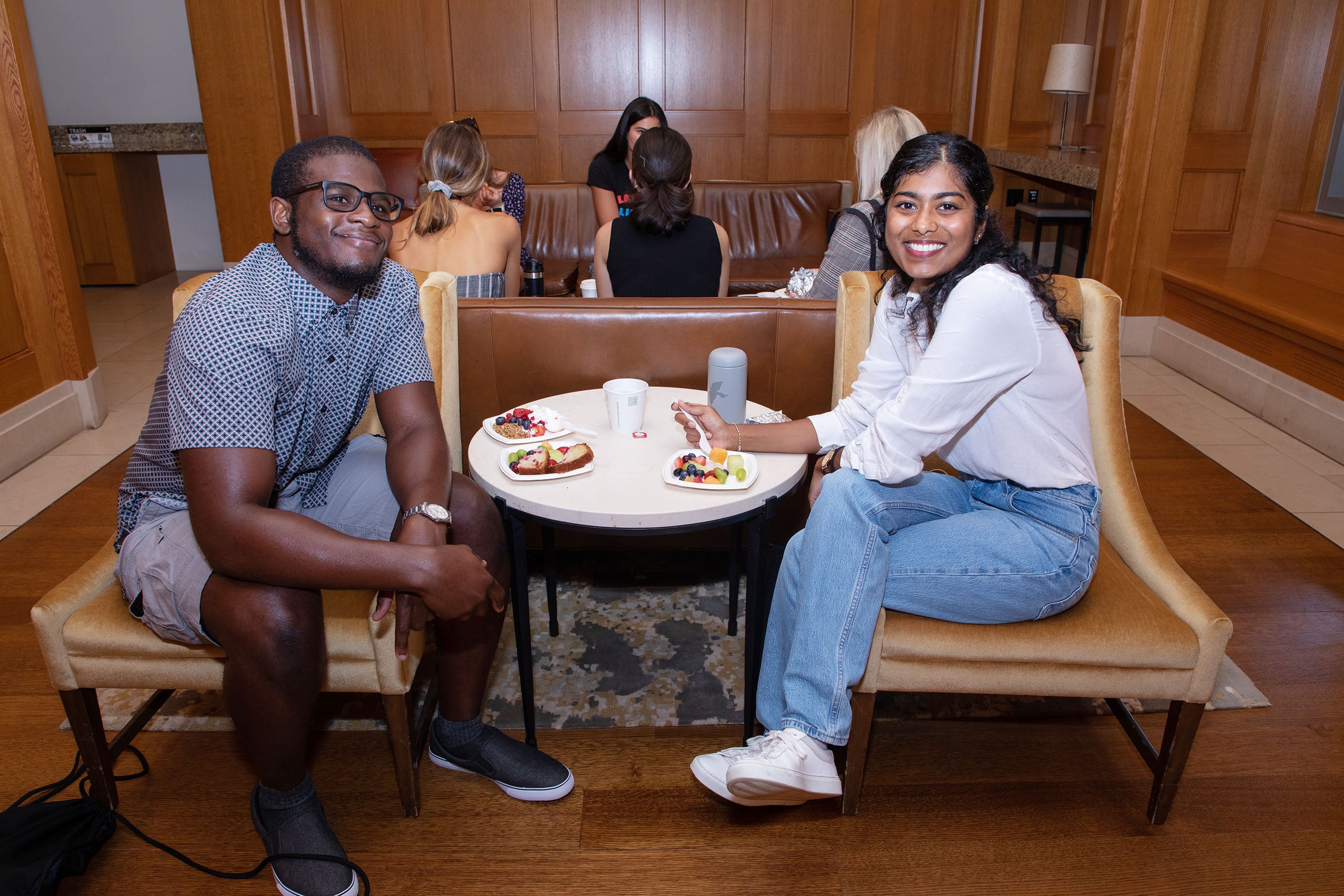 Two students sitting at a small table, smiling for the camera.