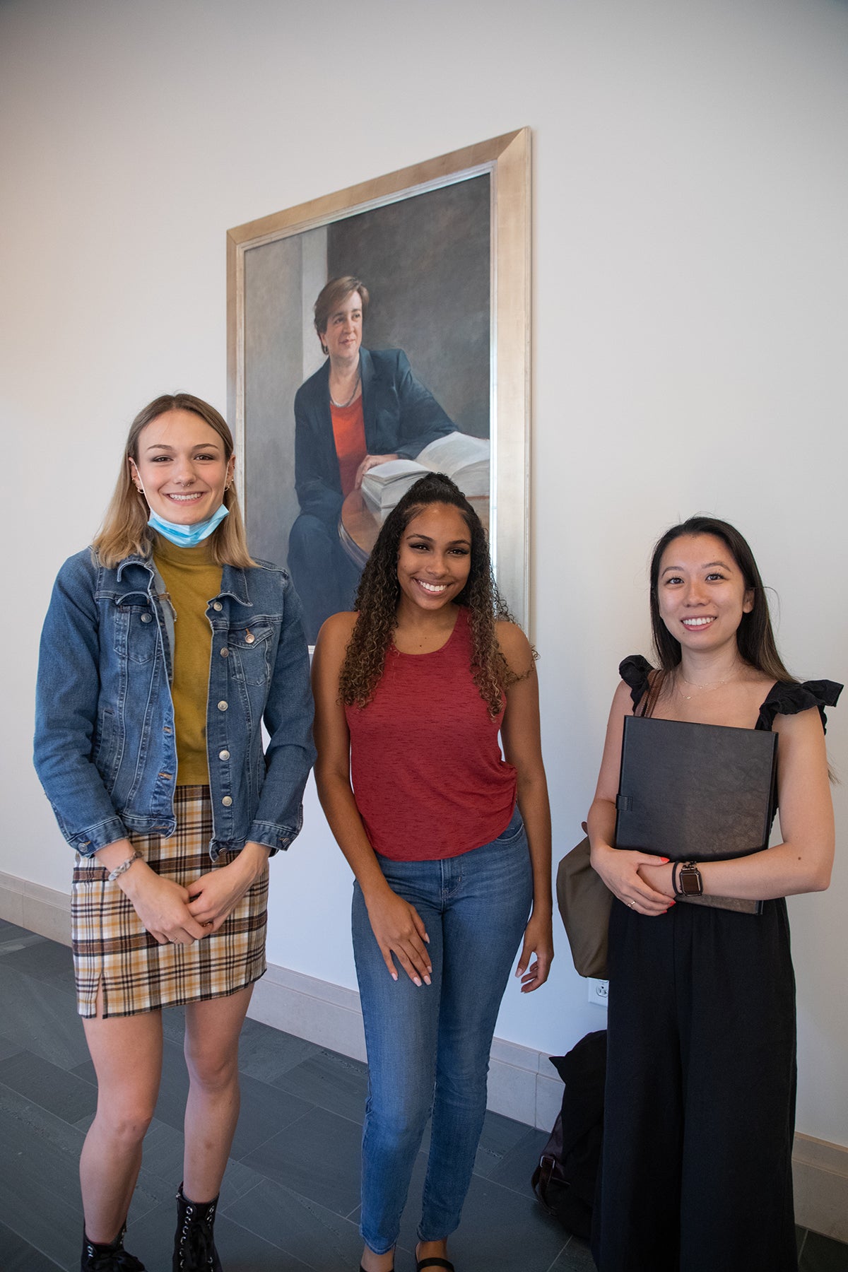 Three students posing in front Justice Kagan's portrait