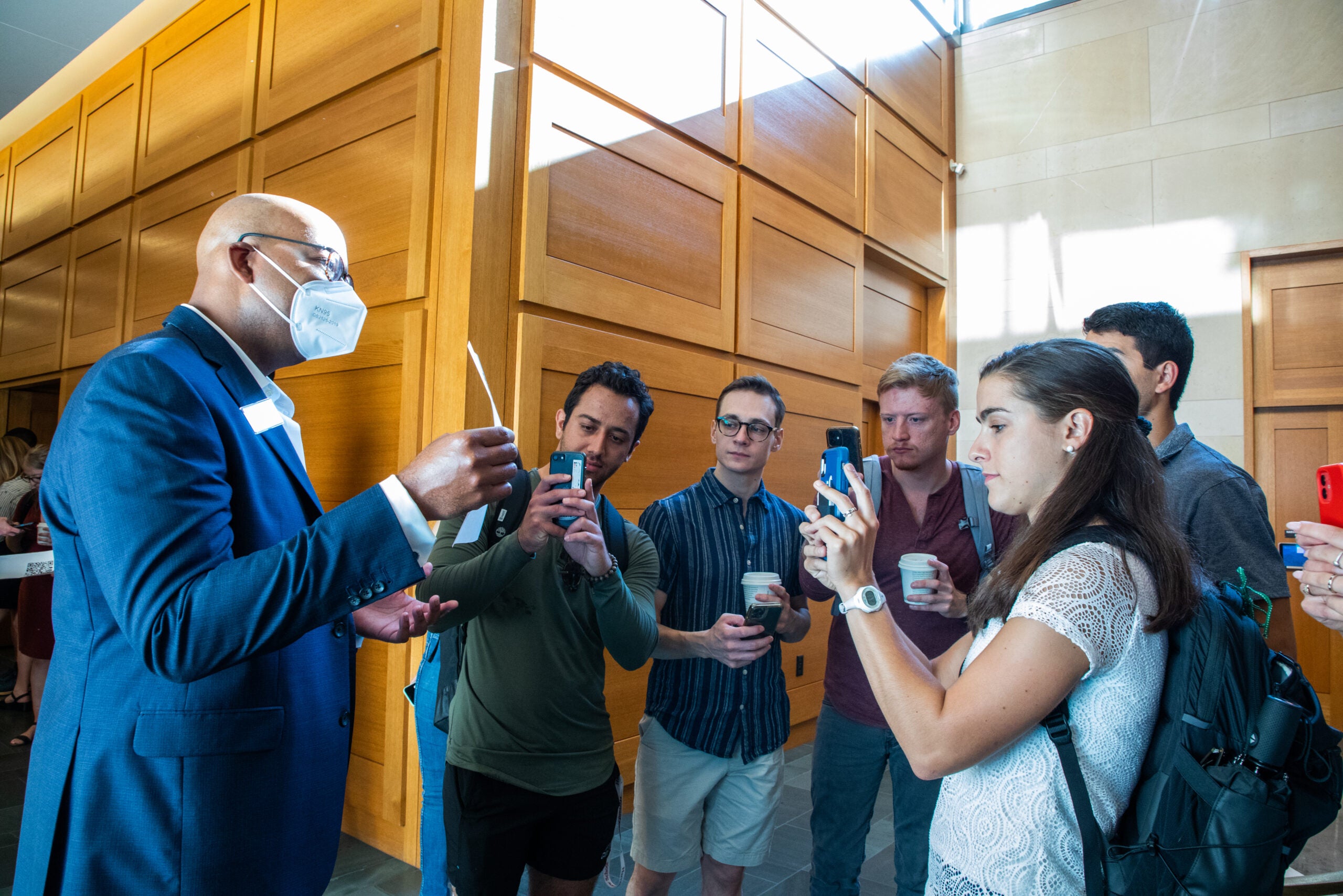 A group of students taking a photos of something Dean of Students Stephen Ball is holding in his hands.