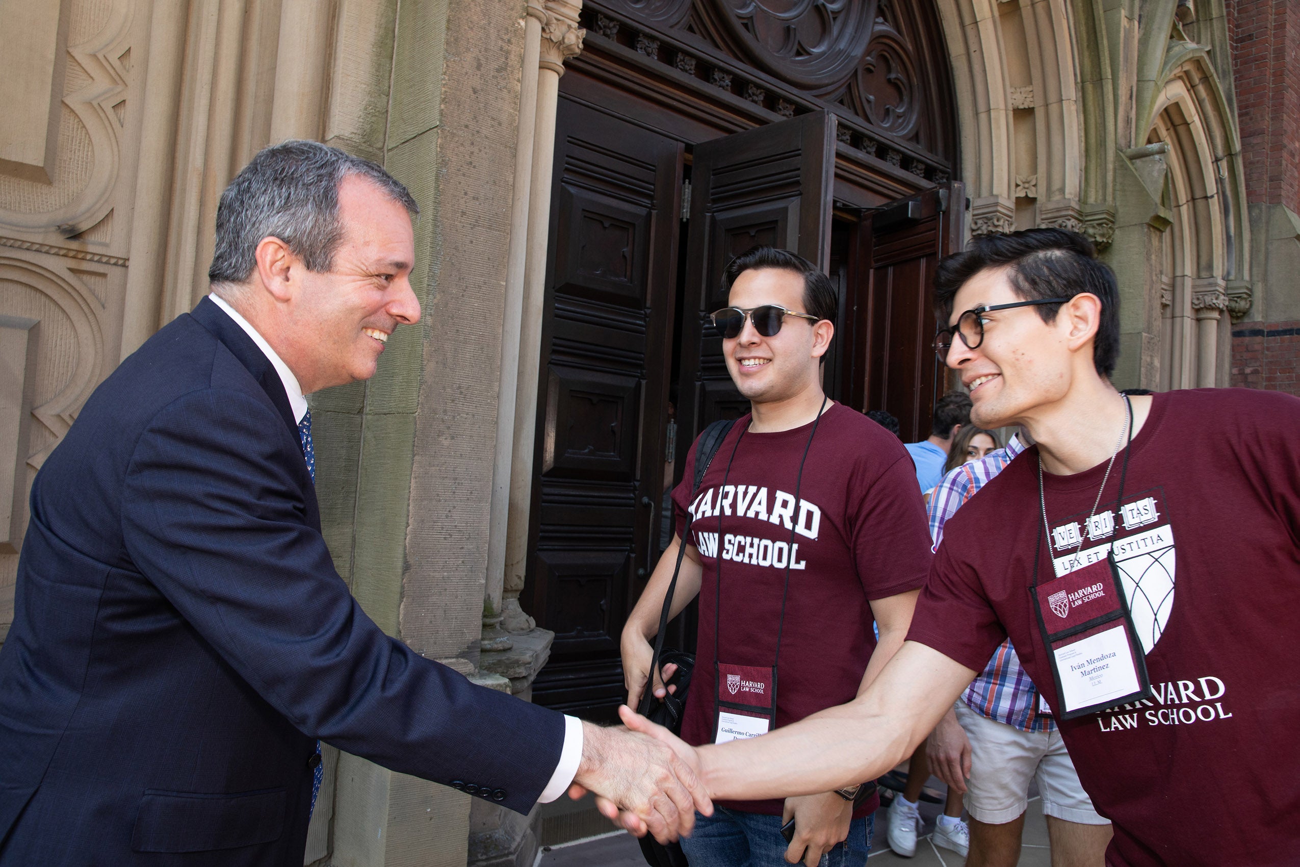 Dean John F. Manning shakes hands with an incoming student outside Sanders Theatre.