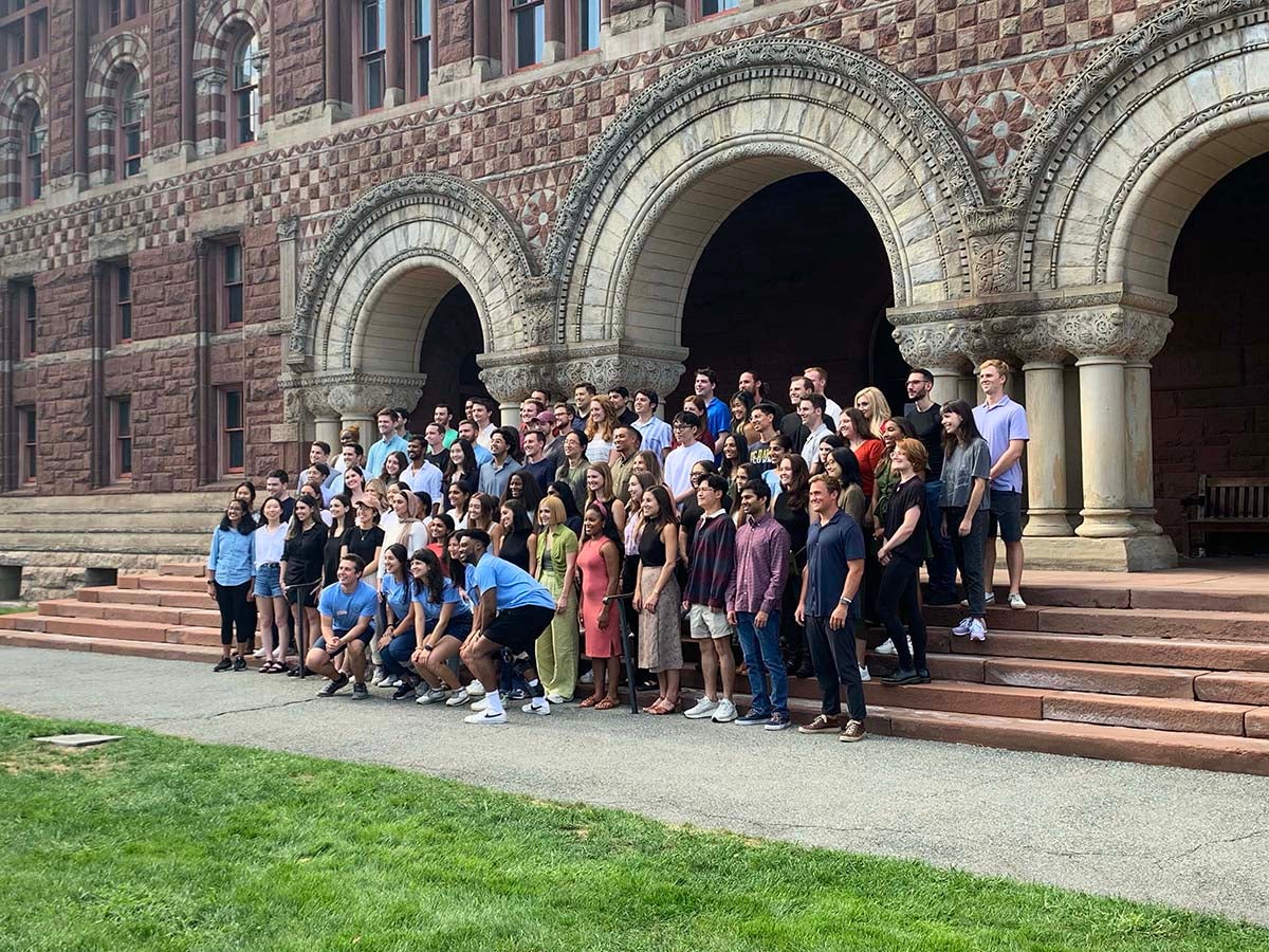 A new section of students poses together on the steps of Austin Hall