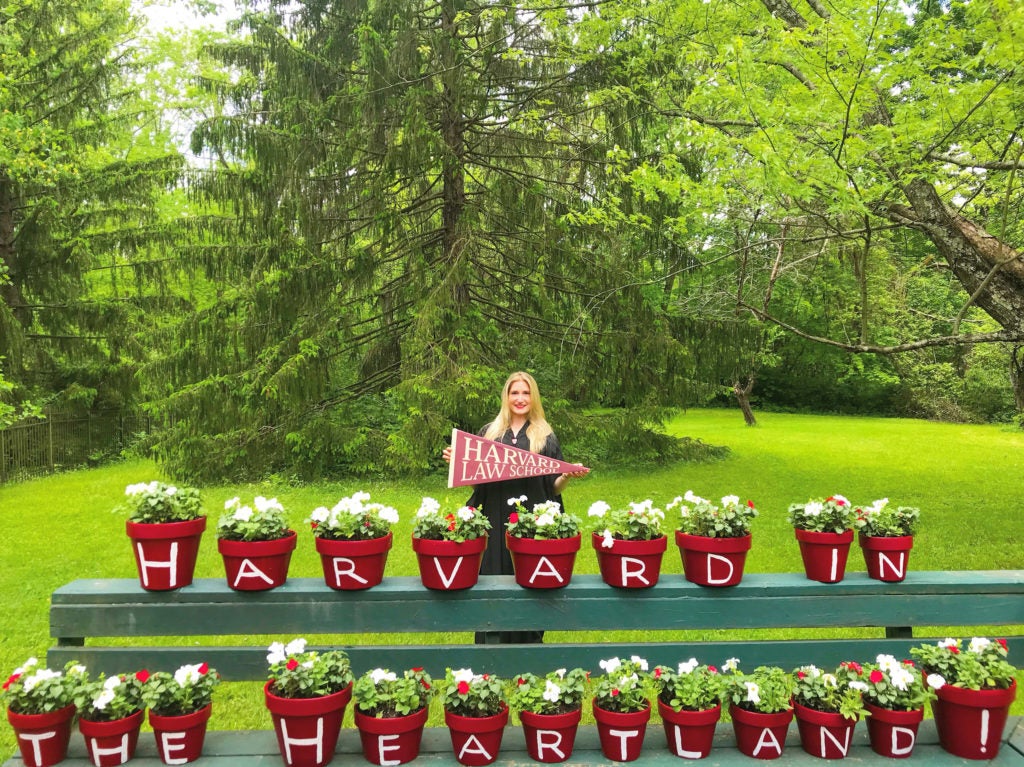 Caroline Shinkle in her backyard behind two rows of flowerpots that spell Harvard in the heartland