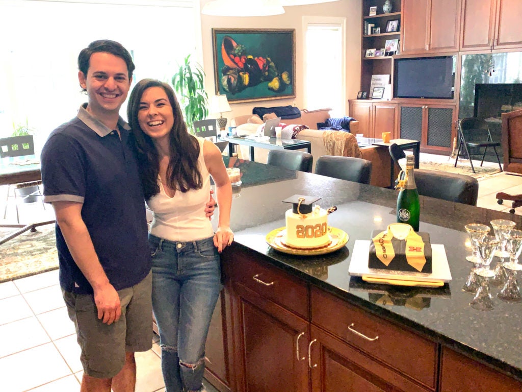 Daniel Egel-Weiss ’20 at home with his fiance a bottle of champagne and a Commencement cake
