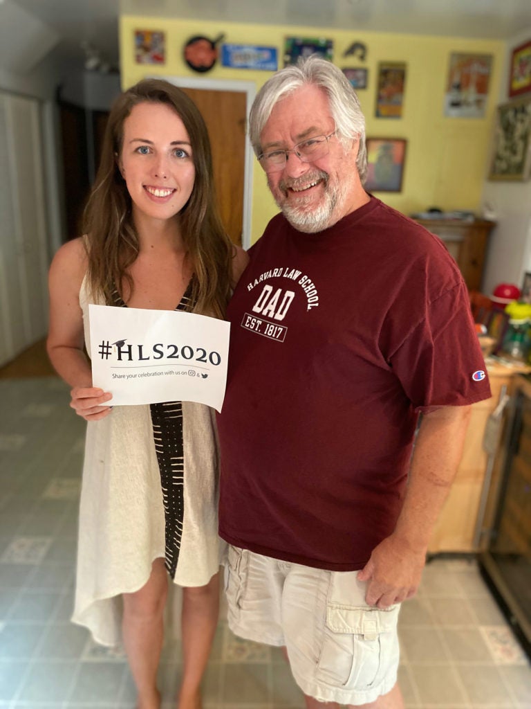 A young woman holding a sign that says HLS2020 poses with her father