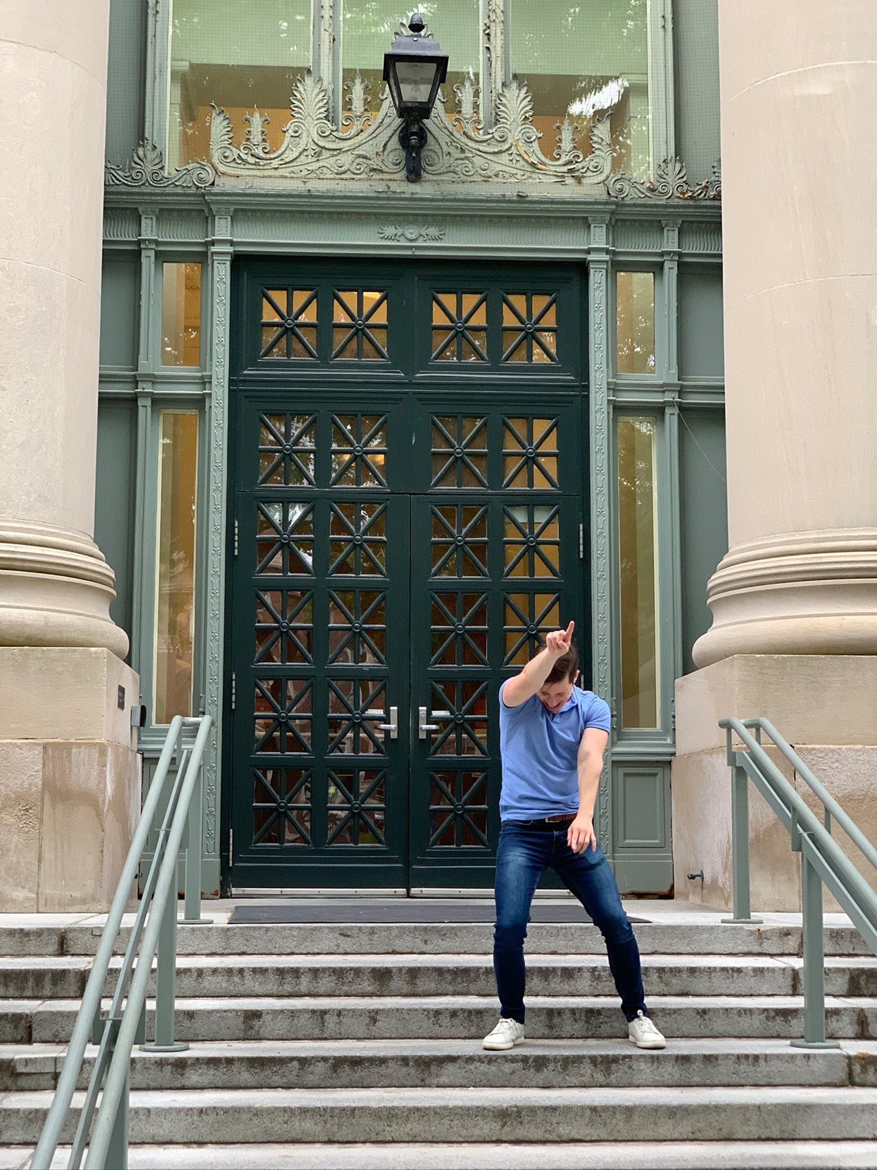 Man wearing a blue shirt dancing in front of a doorway