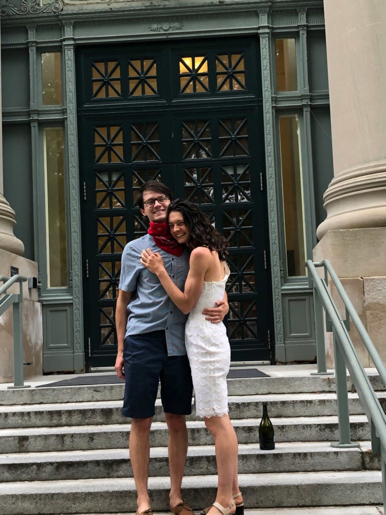 A man and a woman hug on the steps of Langdell Hall