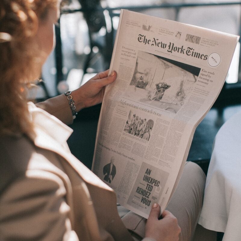 Person sitting down reading the New York Times newspaper.