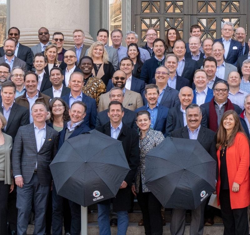 A group of alumni posing on the steps of Langdell Library