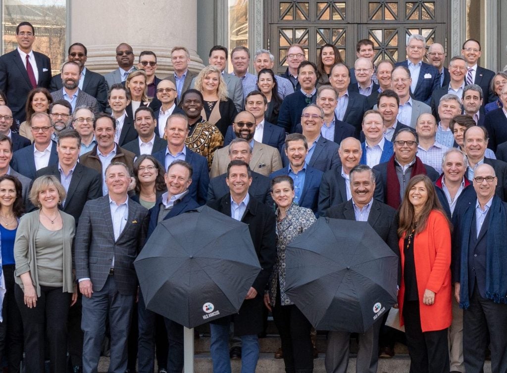 A group of alumni posing on the steps of Langdell Library