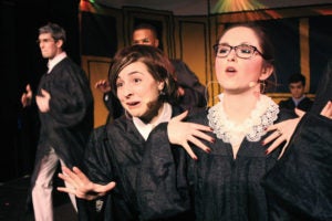 Two women dressed in judges robes perform on stage