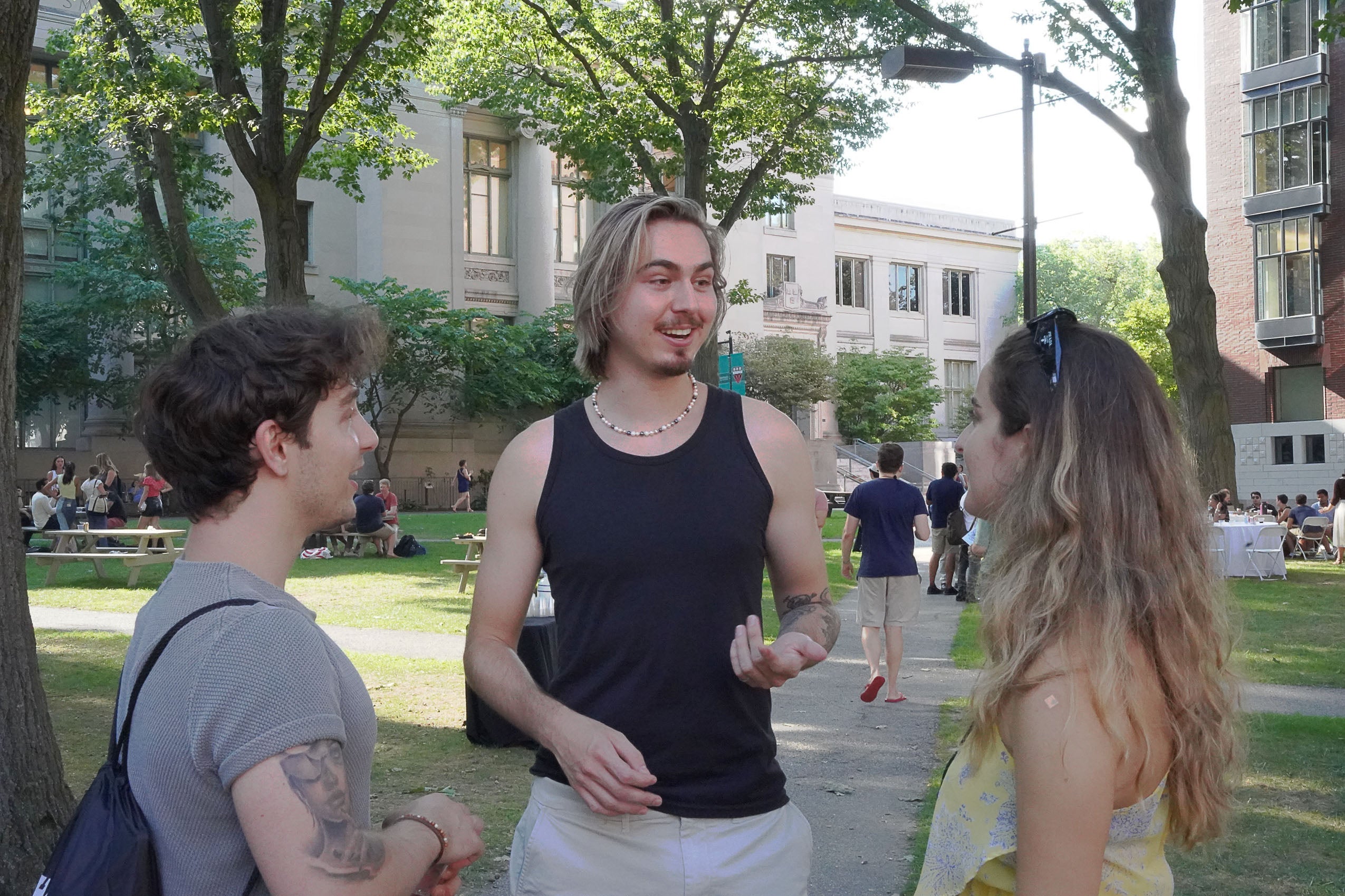 Three students standing outside talking.