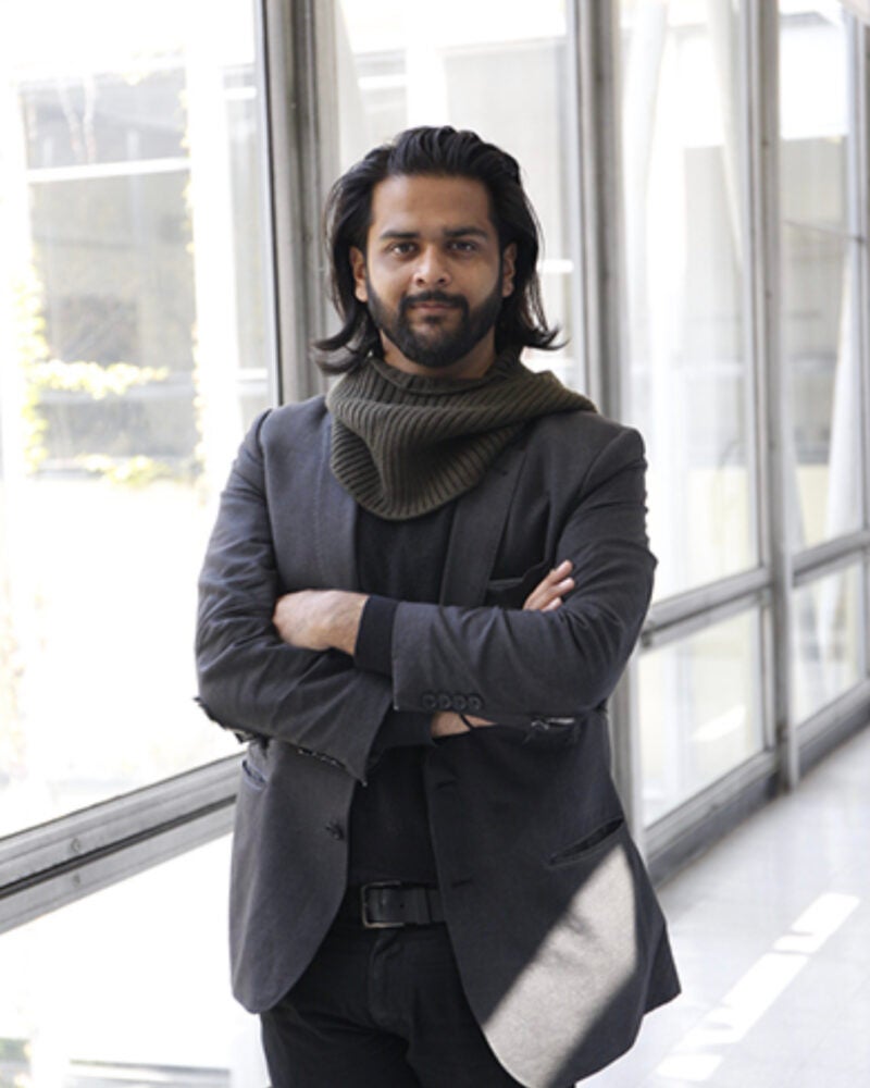 Sankalp Bhatnagar standing with arms crossed in room with glass walls.