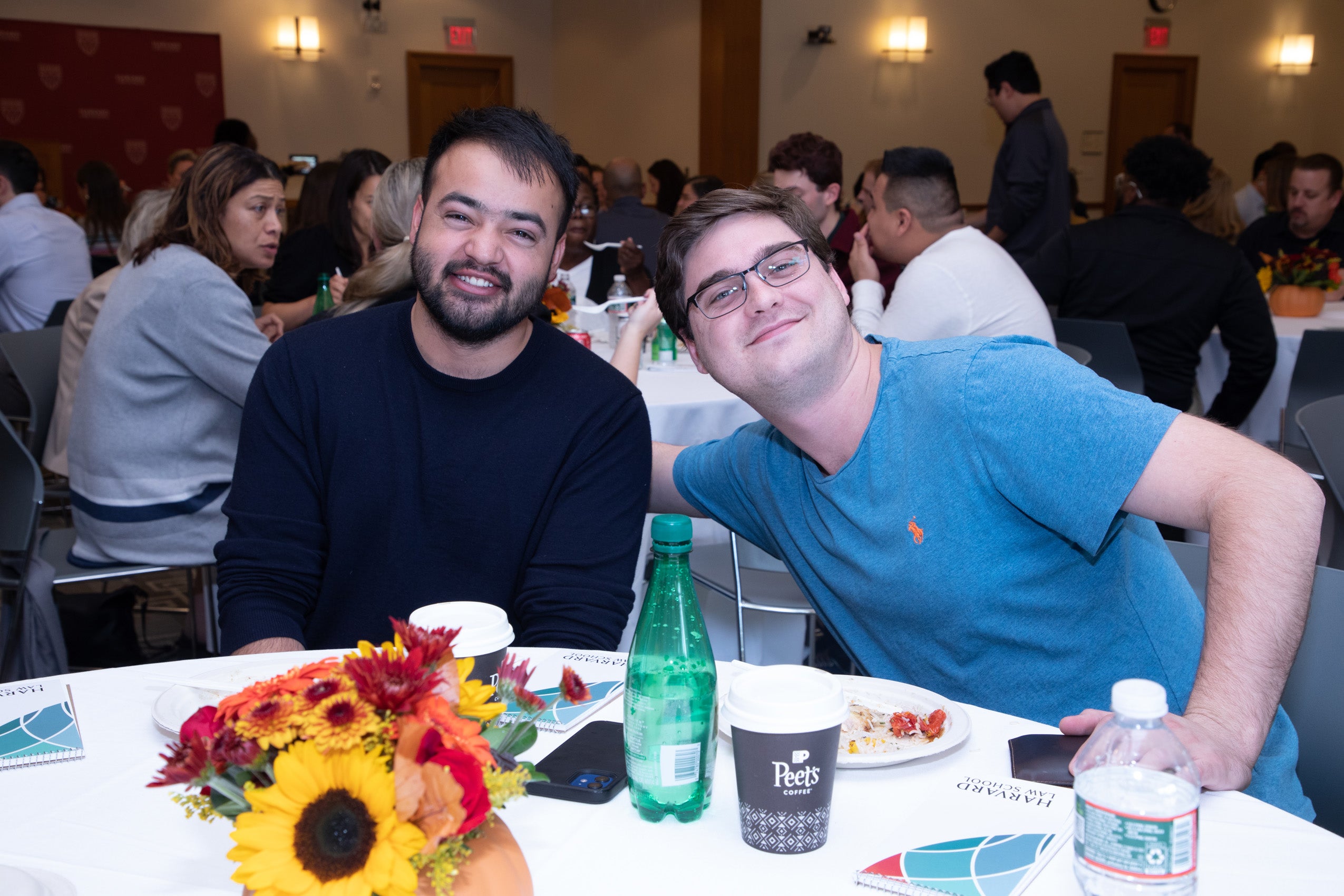 Two men at a table pose for the camera