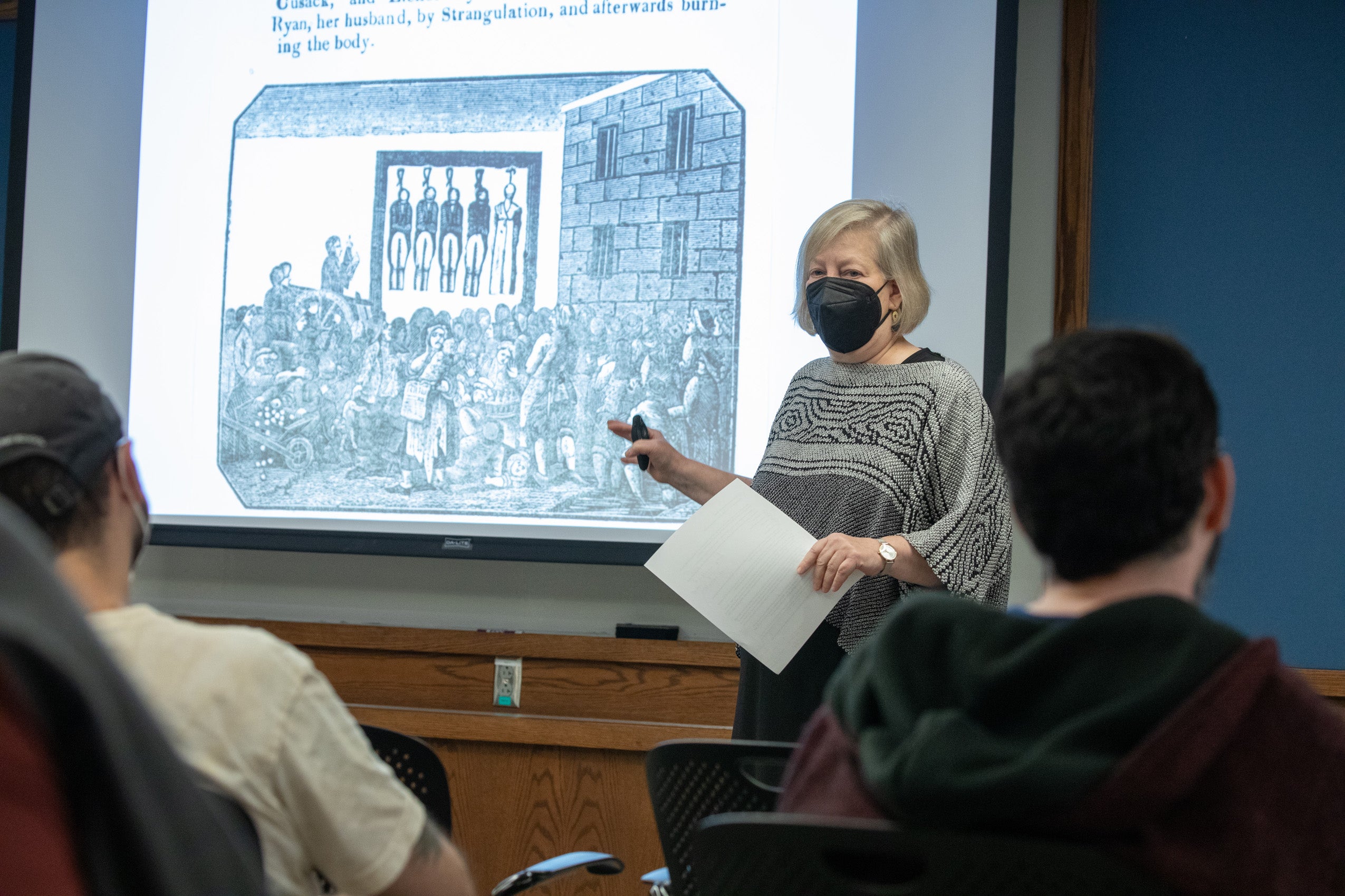 Carol Steiker speaking about a drawing that shows several people being hung in front of a crowd.