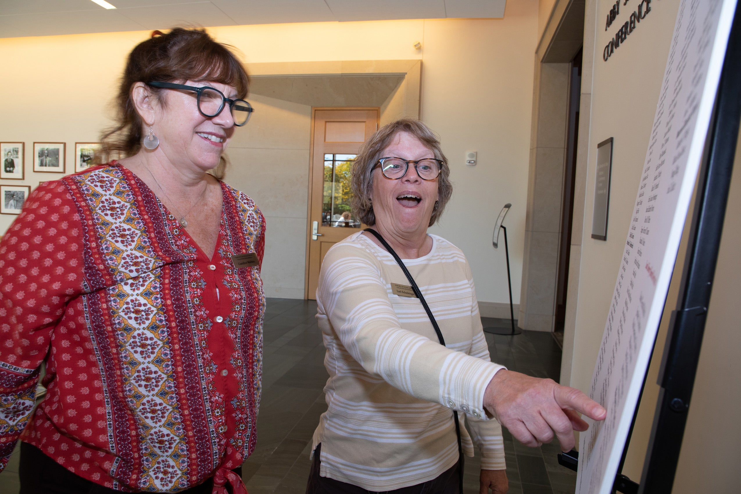 A woman points to a sign as another woman looks on
