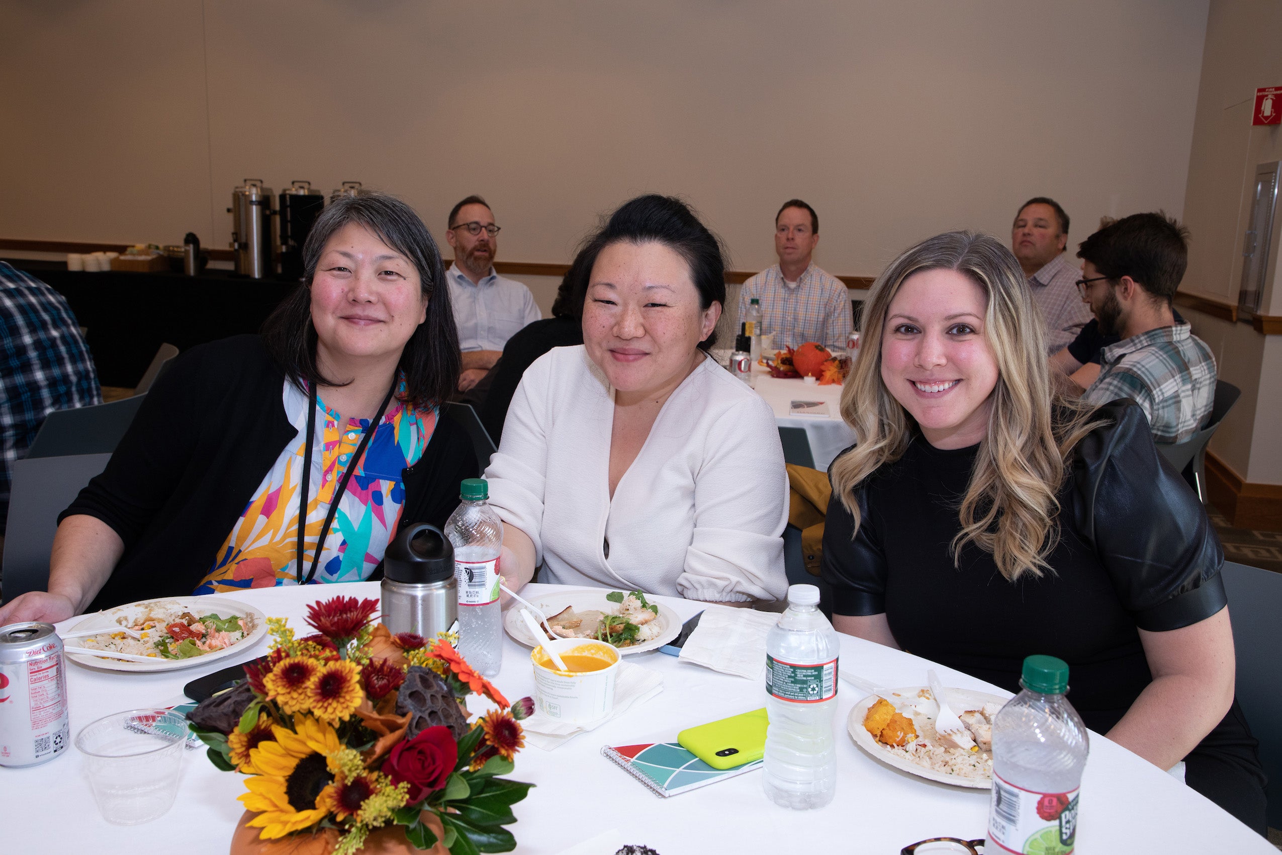Three woman sitting at a table pose for the camera