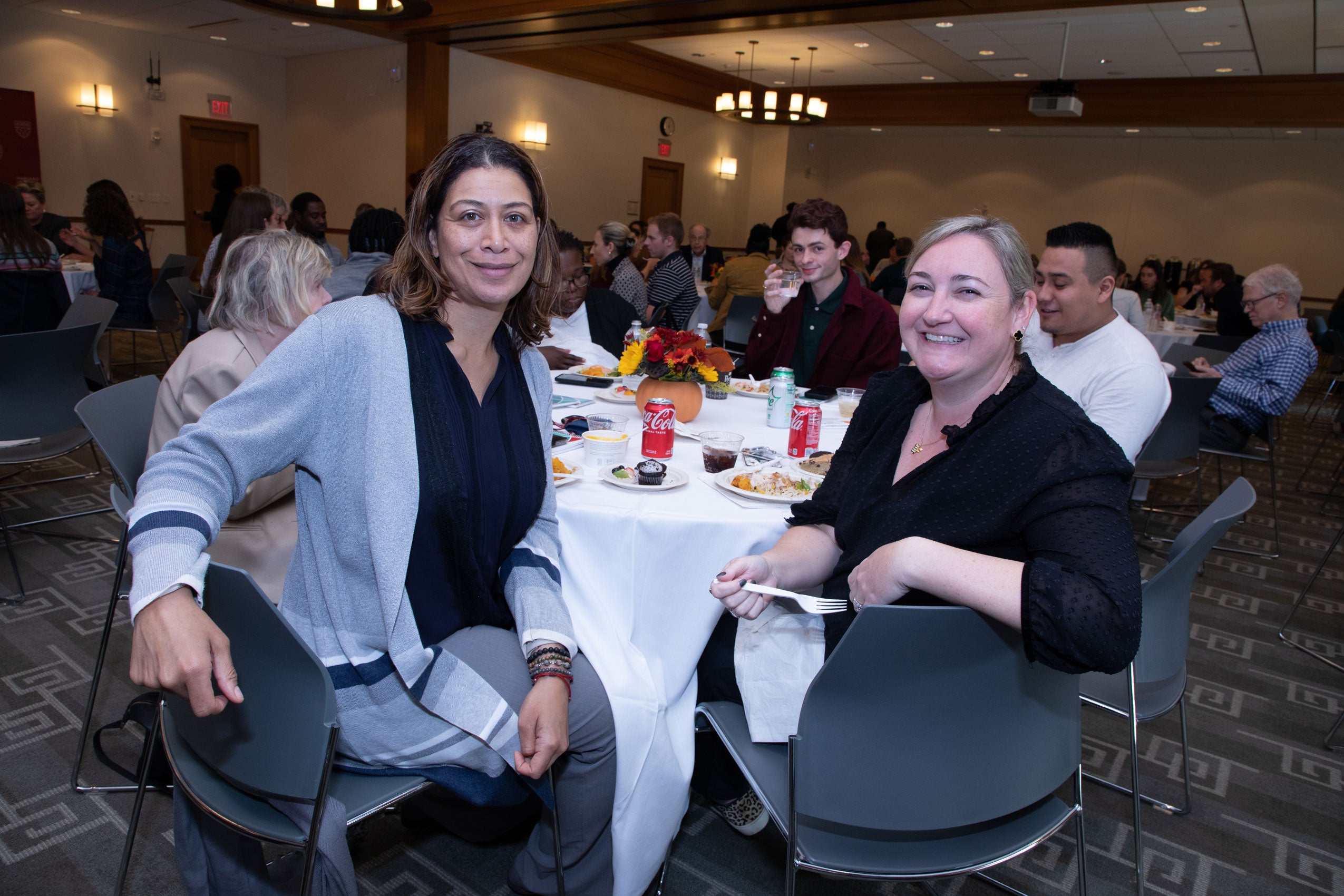 Two women turn from the table to pose for a photo