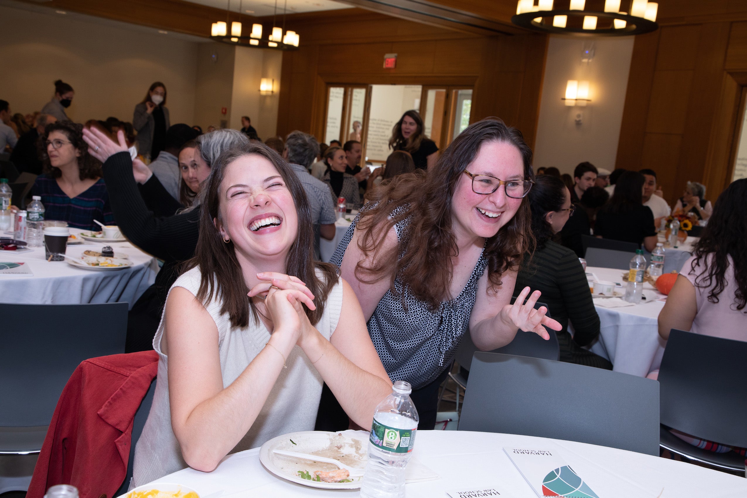 Two women sitting at a table laugh