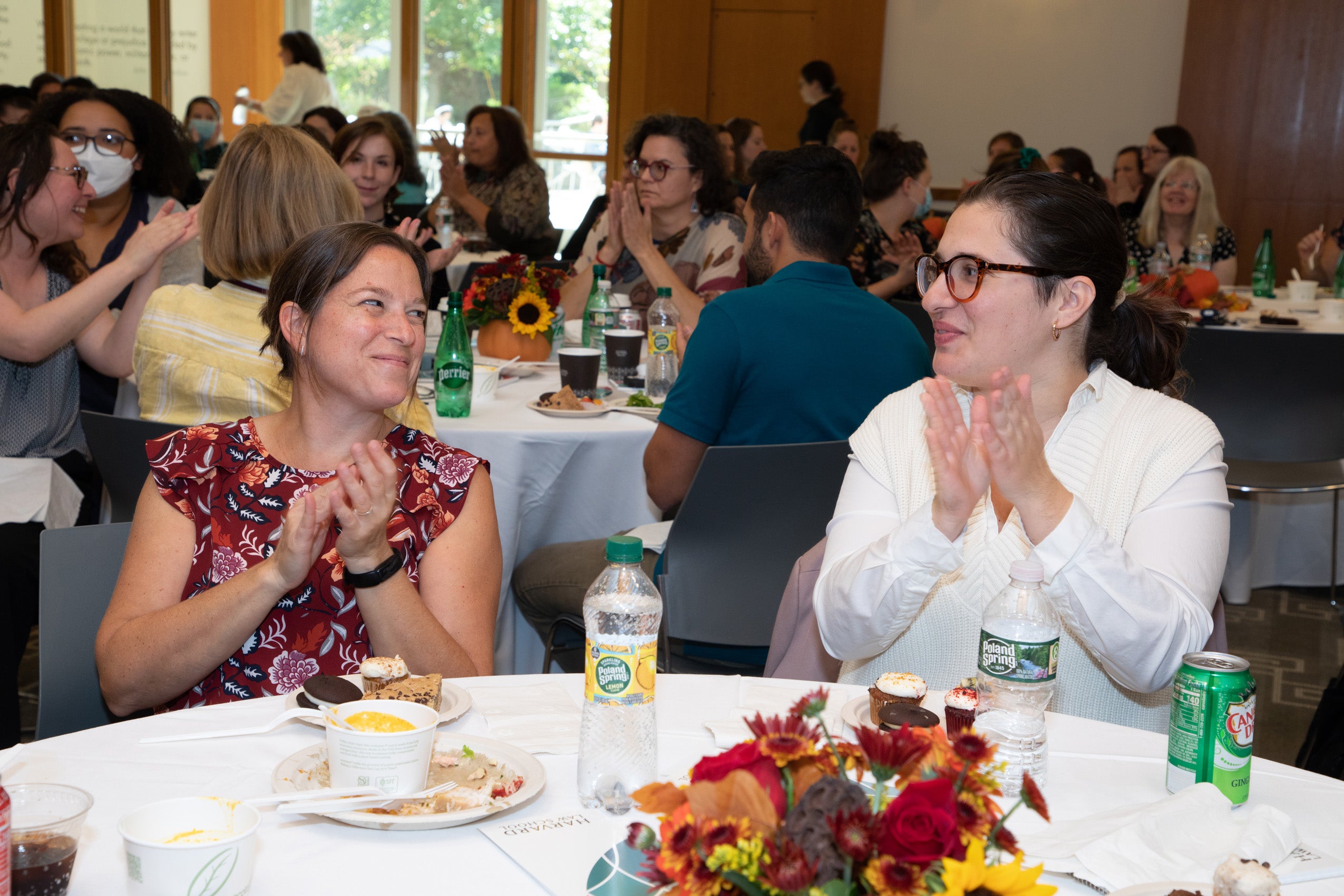 Two women sitting at a table clapping and looking at each other